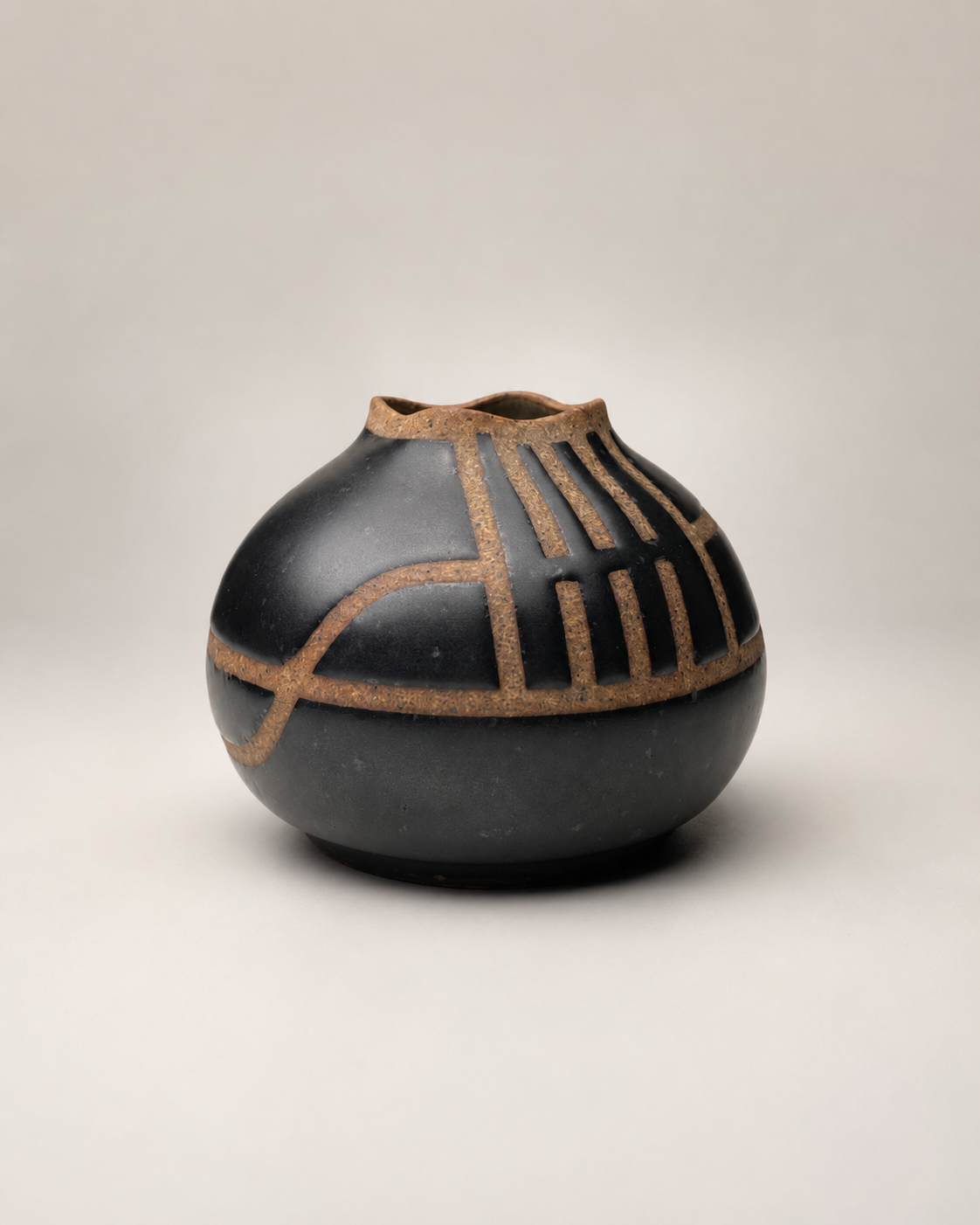 Dark gray ceramic vase with geometric tan patterns on a plain light background.