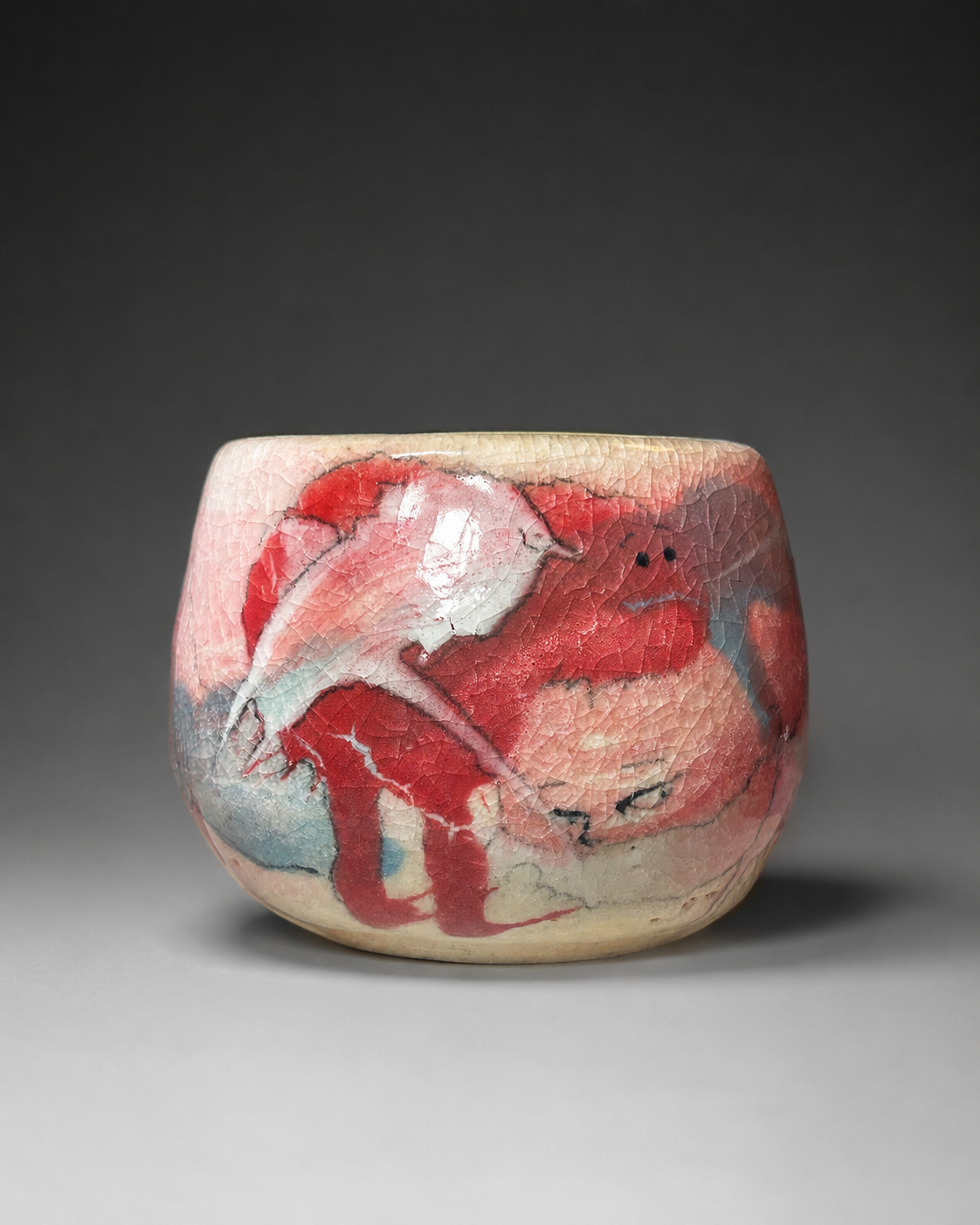 A small ceramic cup with a crackled glaze featuring abstract red, white, and blue brush strokes.