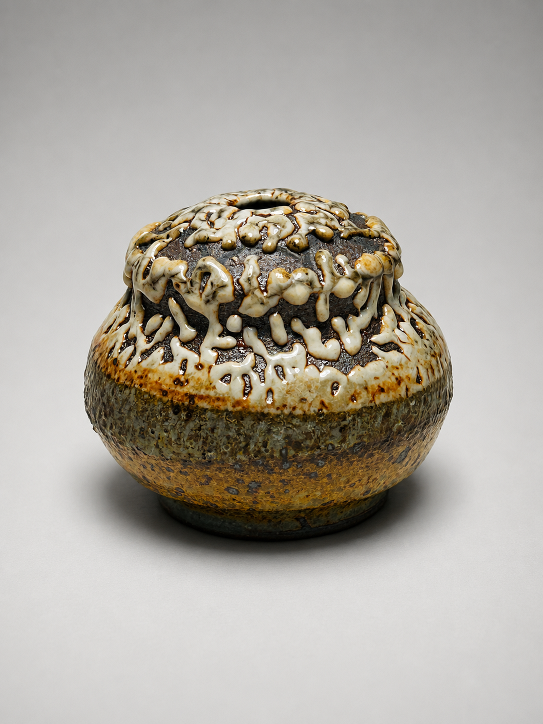 Ceramic bowl with glazed surface, filled with a dark substance, topped with white and brown drizzled sauce.