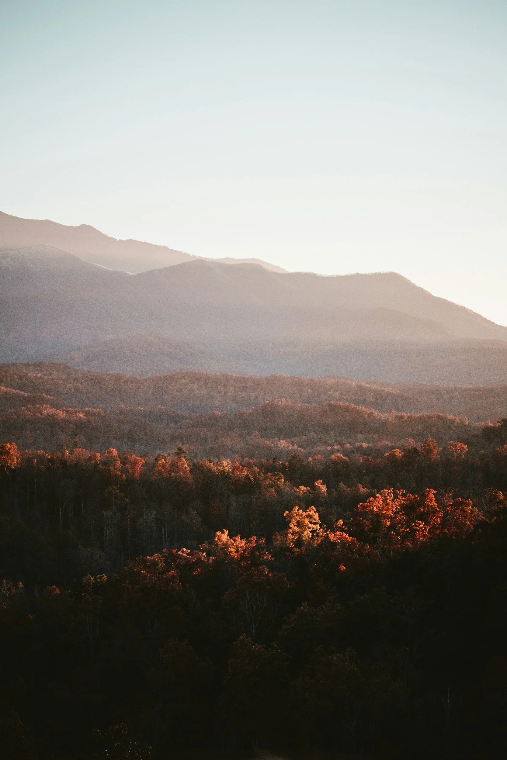 Scenic landscape view of layered hills and mountains at sunset or sunrise with a clear sky.