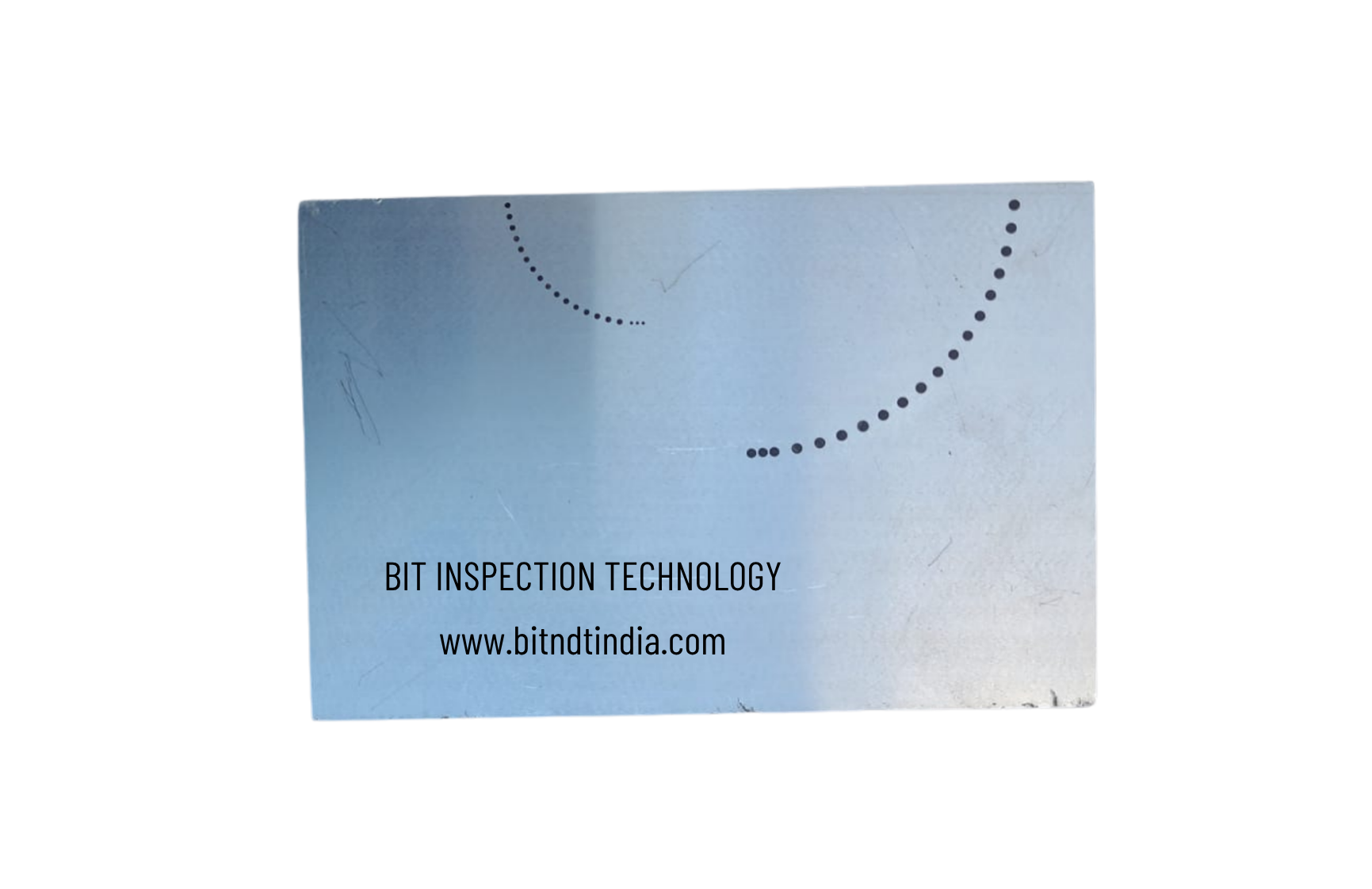 A metallic surface with black dotted lines forming a quarter circle and a more complete arc, with text that reads 'BIT INSPECTION TECHNOLOGY' and a website URL 'www.bitndindia.com'.