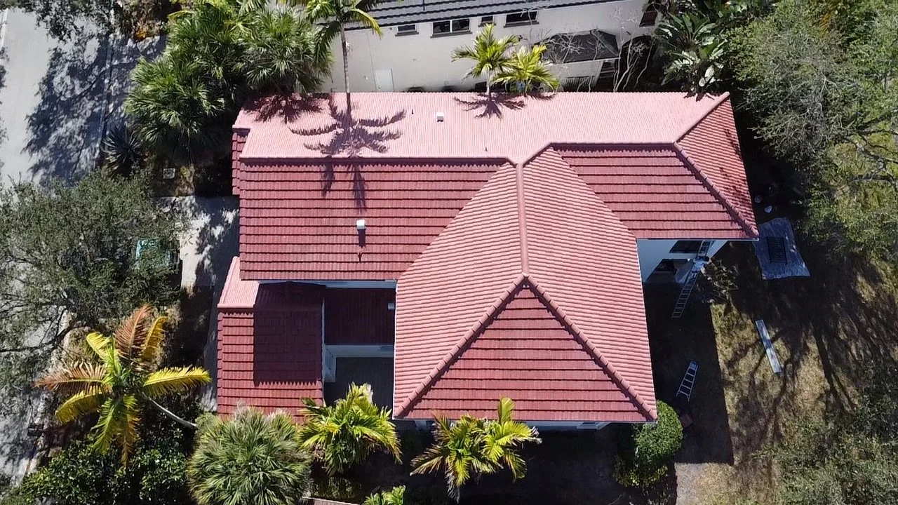 Aerial drone view of a red tile roof on a residential South Florida home surrounded by palm trees.
