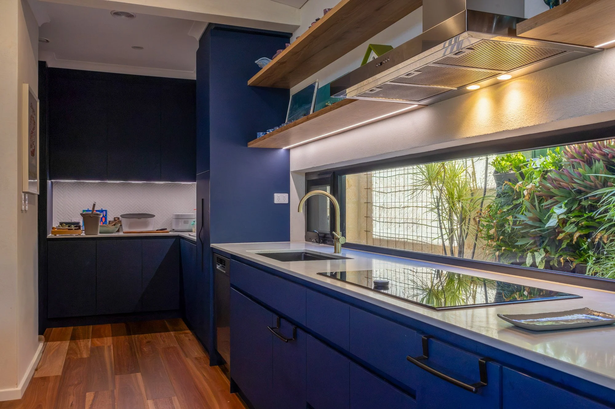 Contemporary kitchen in Courtyard Hempcrete House in Nedlands with dark blue cabinetry and garden outlook