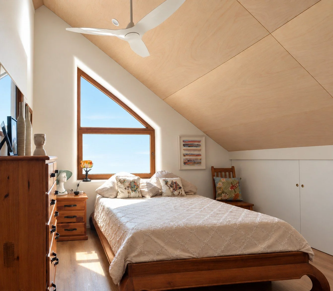 Light-filled bedroom in sustainable Witchcliffe Ecovillage home with timber-lined ceiling and large window