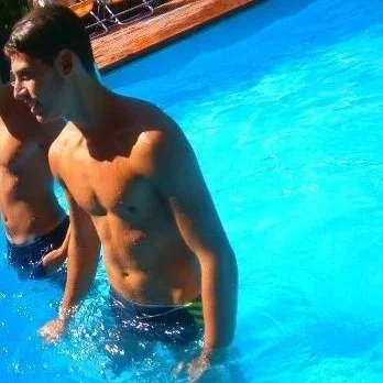 Ragazzo adolescente in piedi in piscina con acqua blu