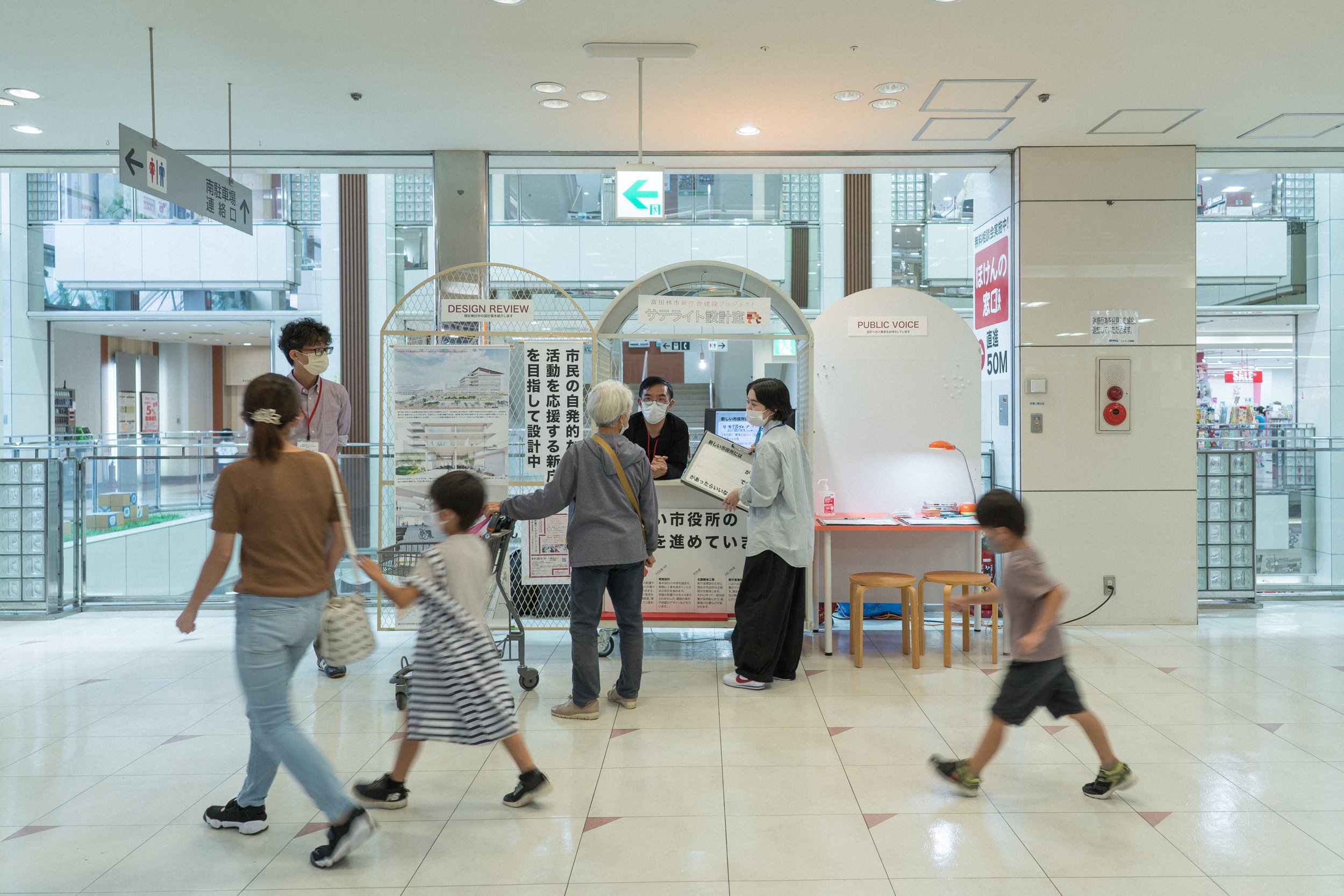 ショッピングモールの案内カウンターと人々の様子。