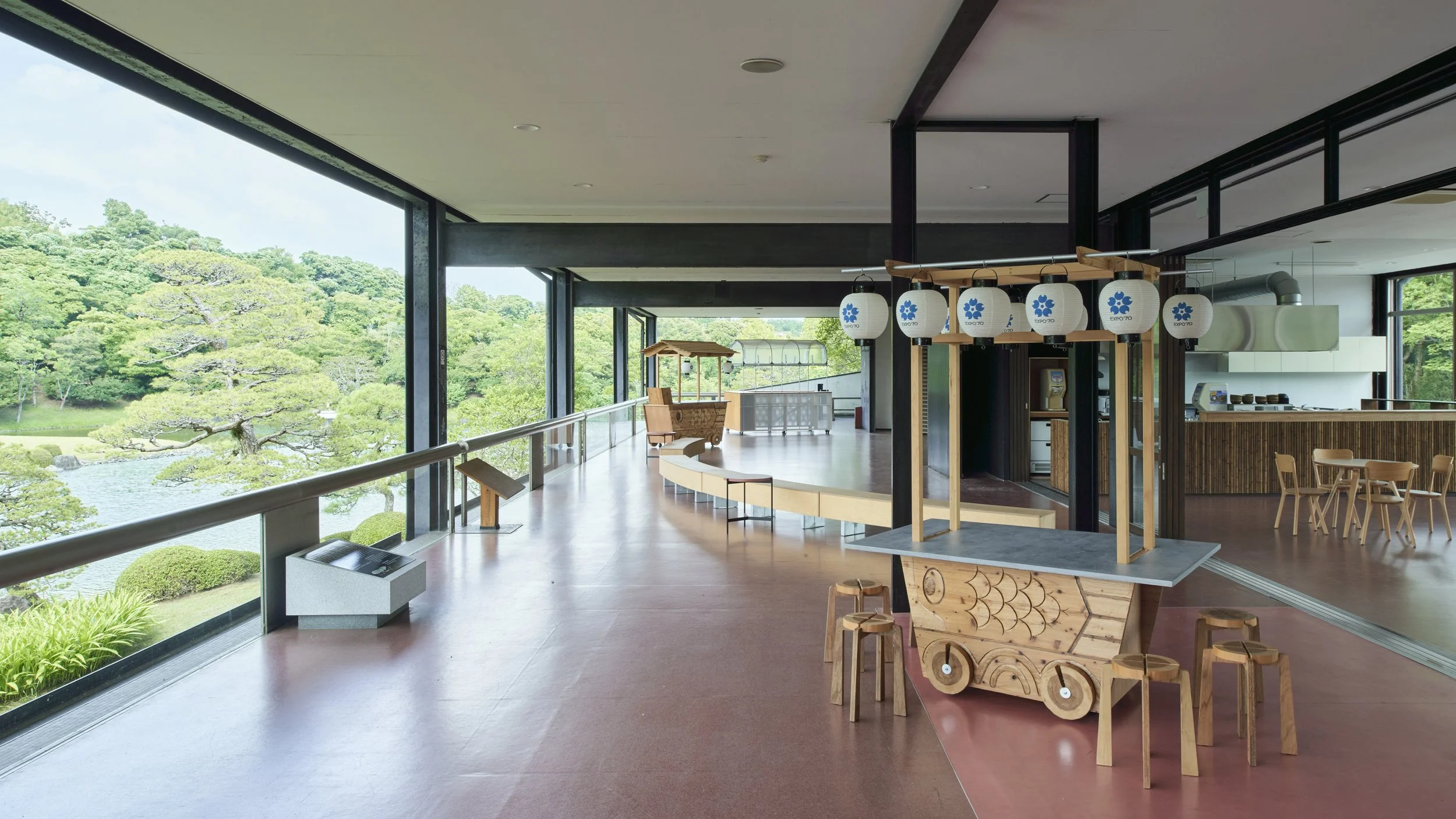 木製の車のおもちゃと提灯が飾られた室内の風景。大きな窓から庭園と木々が見える。