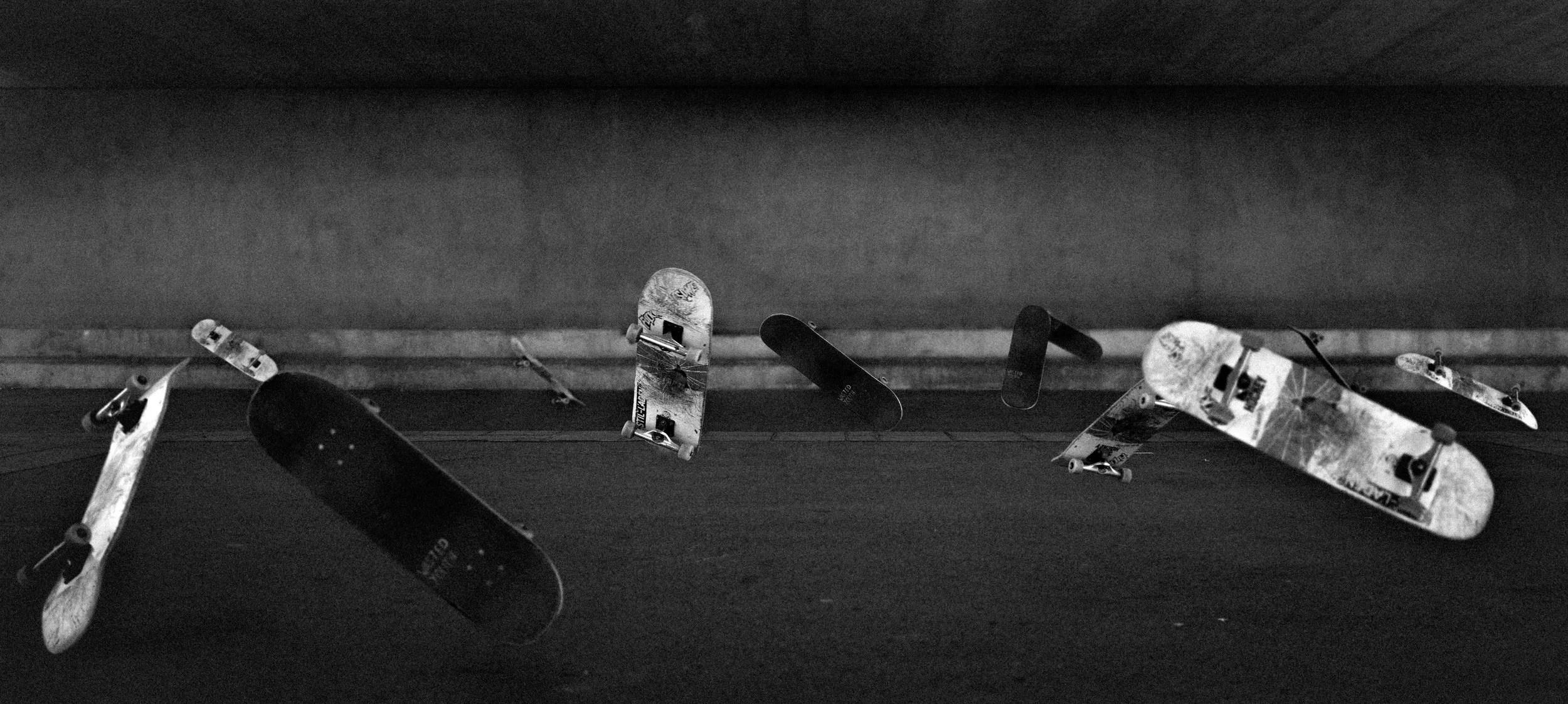 Mehrere Skates an der Wand in einem Skaterpark, schwarz-weiß