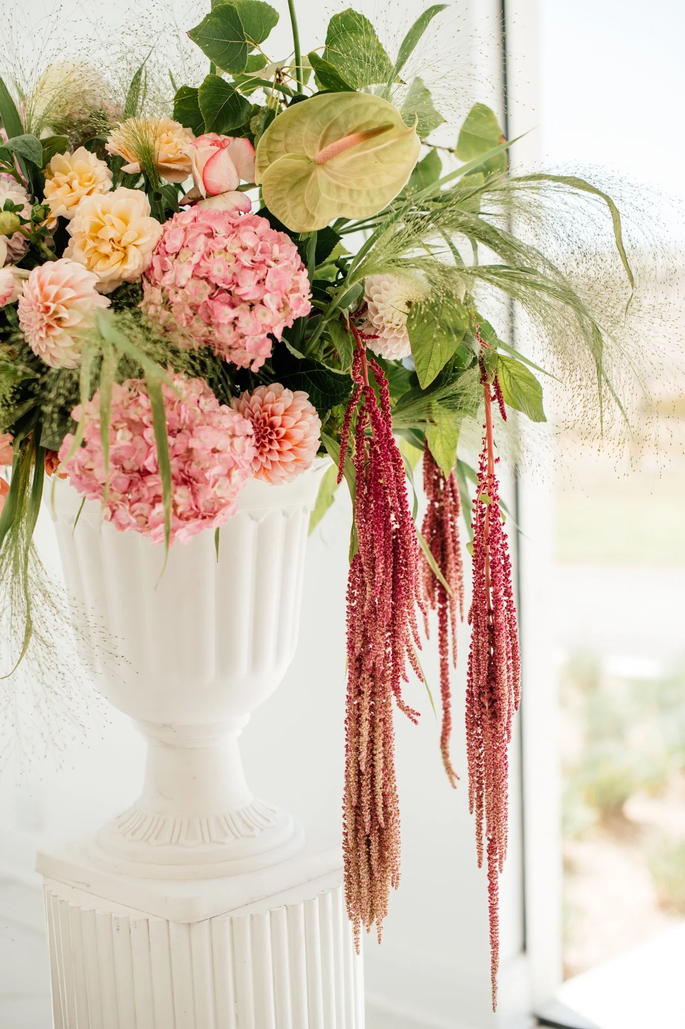 A floral arrangement of pink, peach, and white flowers, including hydrangeas and dahlias, accented with greenery, in front of a window with soft natural light at Loch Lynne wedding venue in Cape Town.