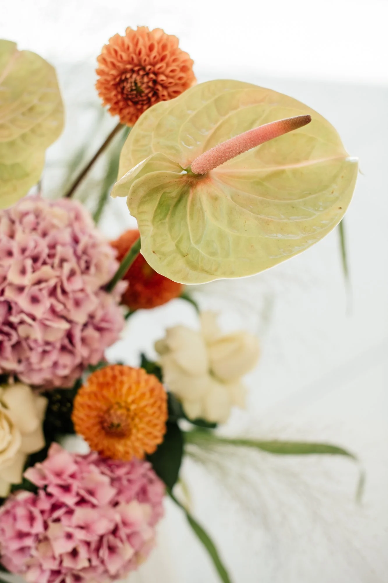 Close-up of a floral bouquet with a prominent anthurium flower and various other colorful flowers.