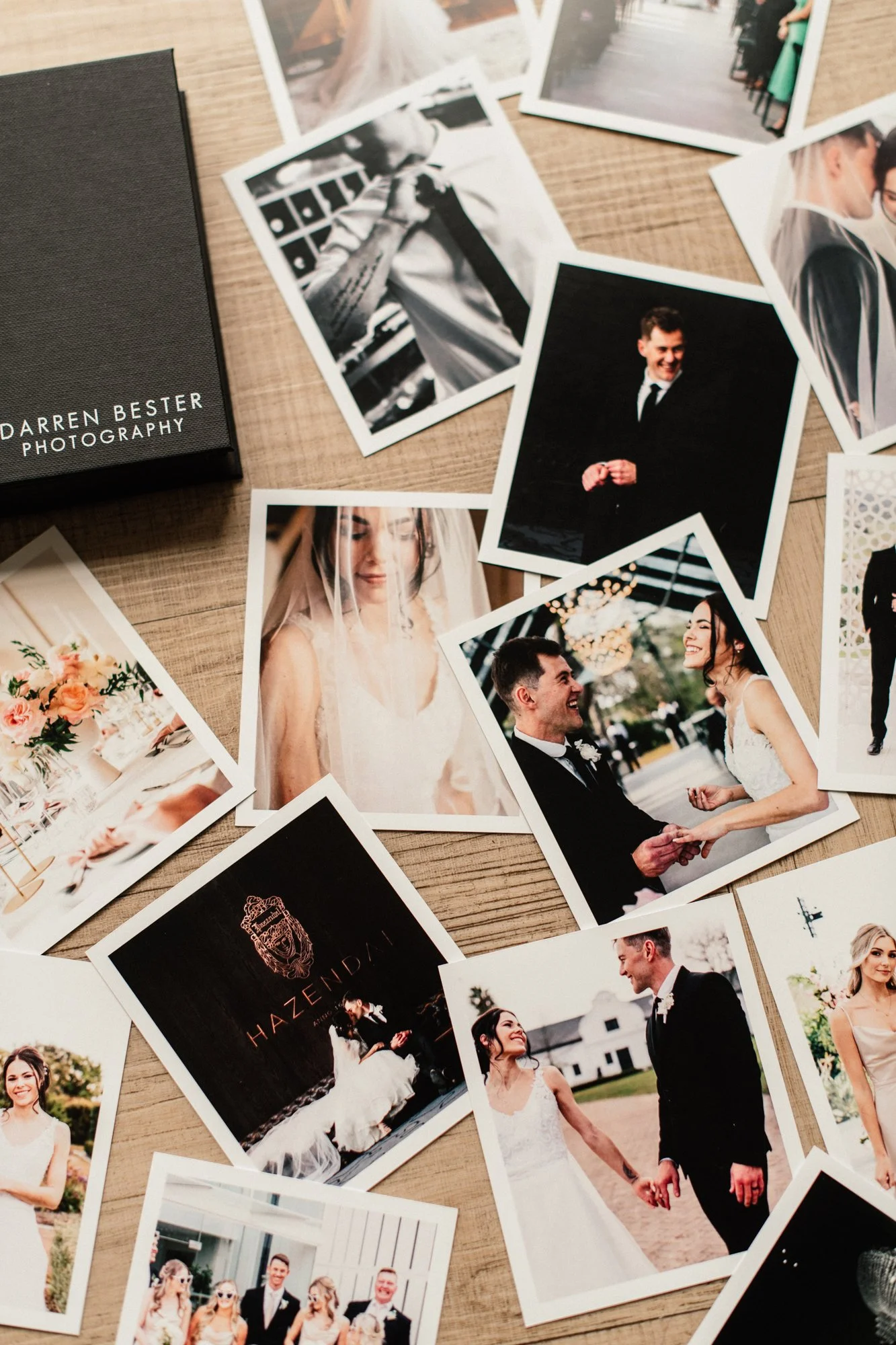 Printed photographs spread across a wooden surface, featuring scenes from a wedding, including the bride and groom, wedding party, and wedding reception, along with a black box labeled 'Darren Bester Photography'.