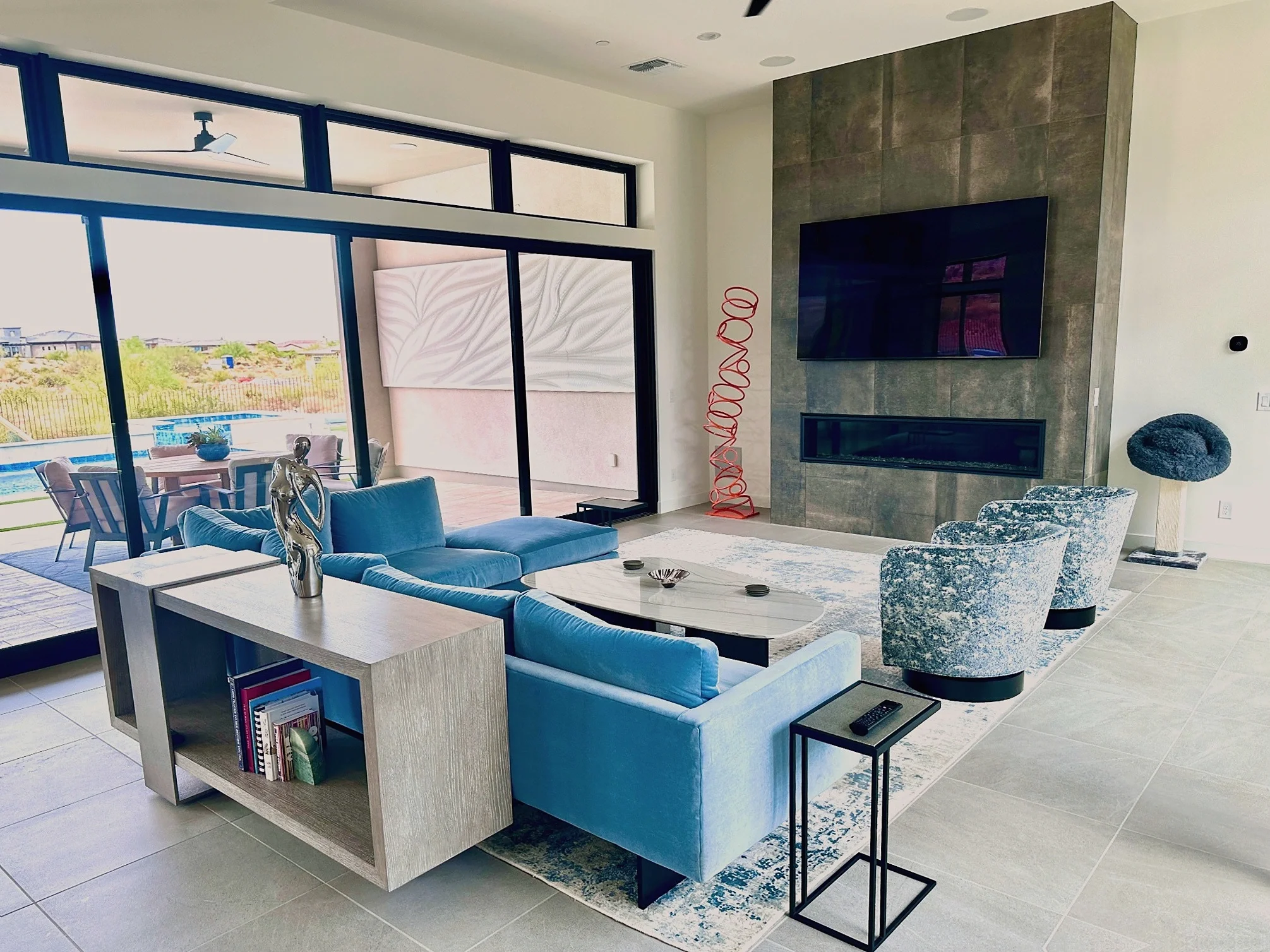 Luxury great room with blue seating, fireplace and indoor-outdoor views at Sereno Canyon in North Scottsdale
