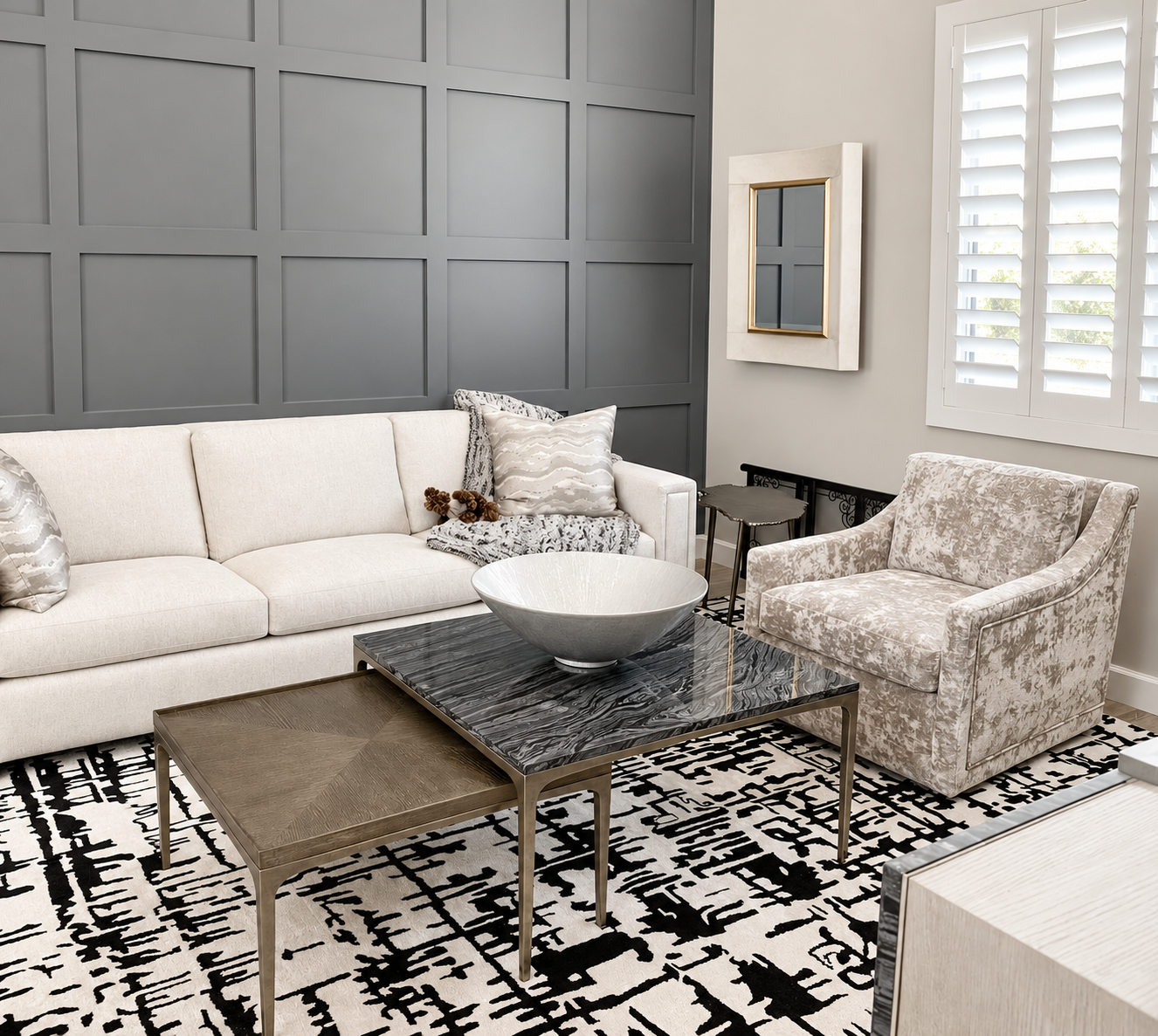 Living room with a modern television mounted on the wall, a marble and metal console table, a patterned black and white rug, a beige sofa, a glass-topped coffee table, a standing lamp, and window blinds.