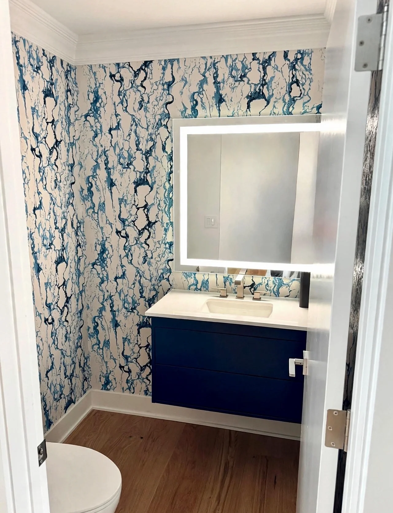 Luxury powder room with blue-and-white abstract wallpaper and floating navy vanity at Gainey Ranch in Scottsdale