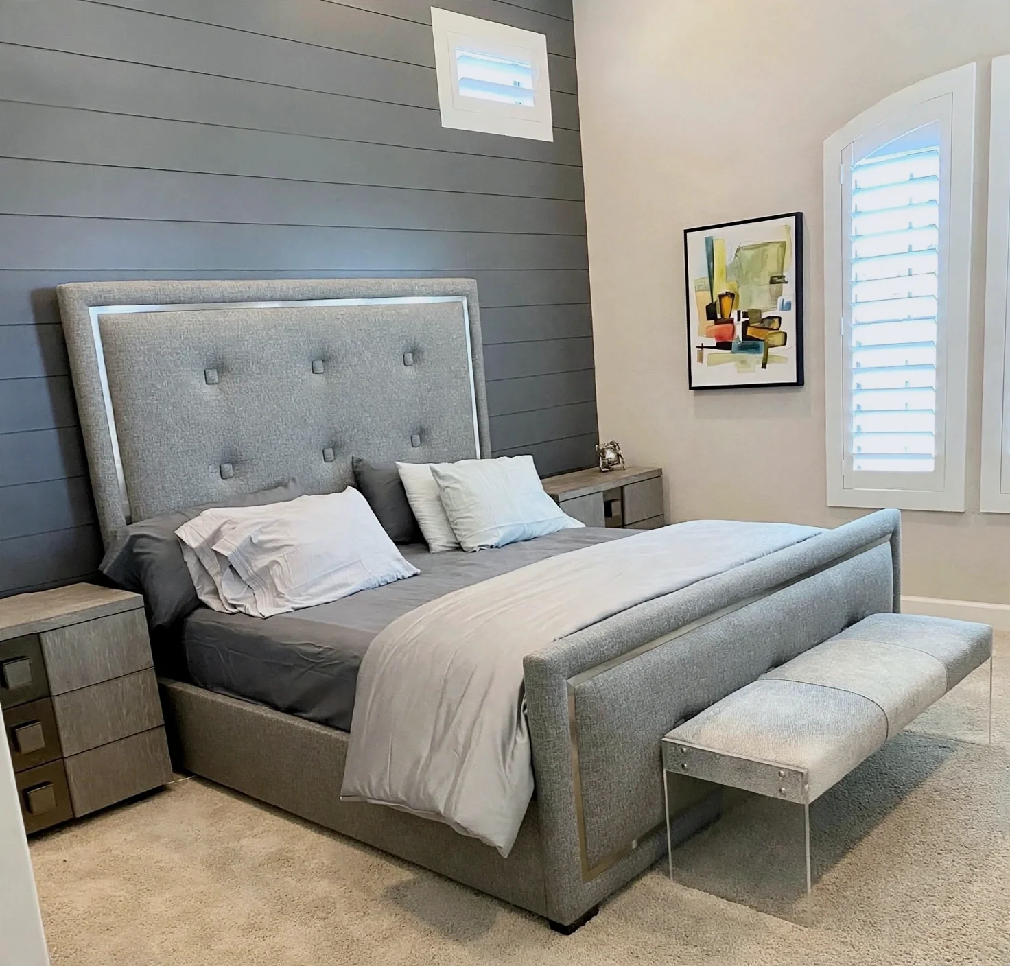 Primary bedroom with gray upholstered bed, paneled accent wall and contemporary art in Scottsdale
