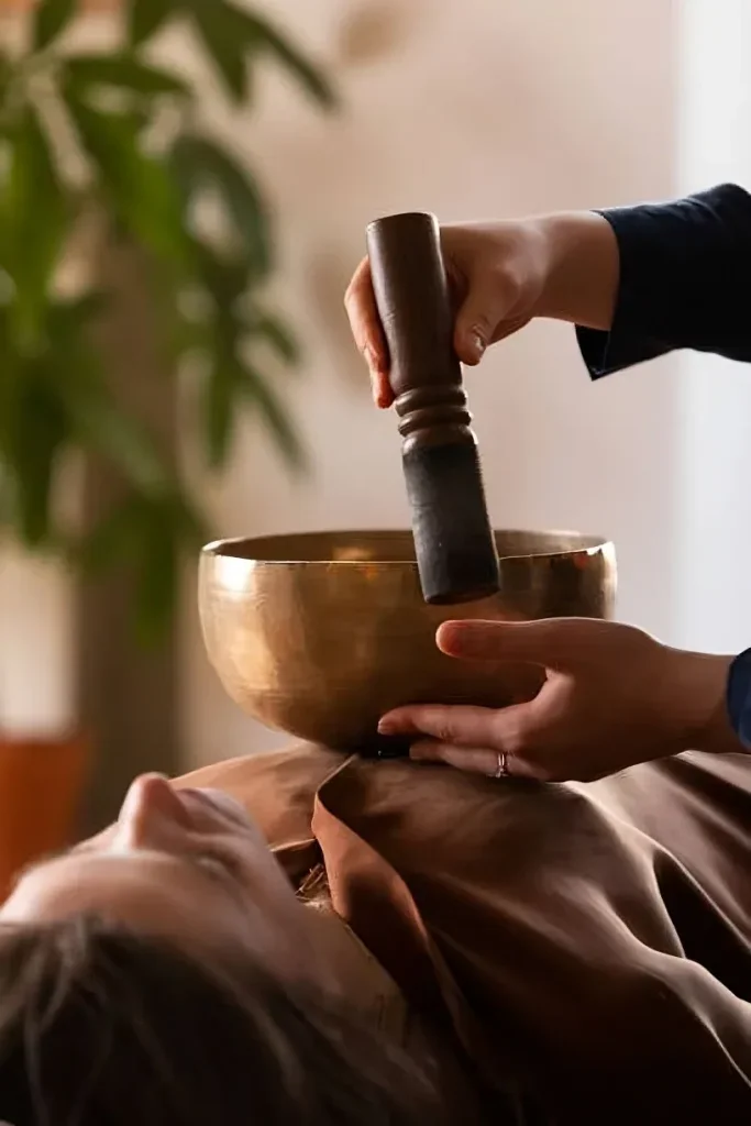Une personne allongée reçoit une thérapie au bol de cristal, une pratique de relaxation sonore.