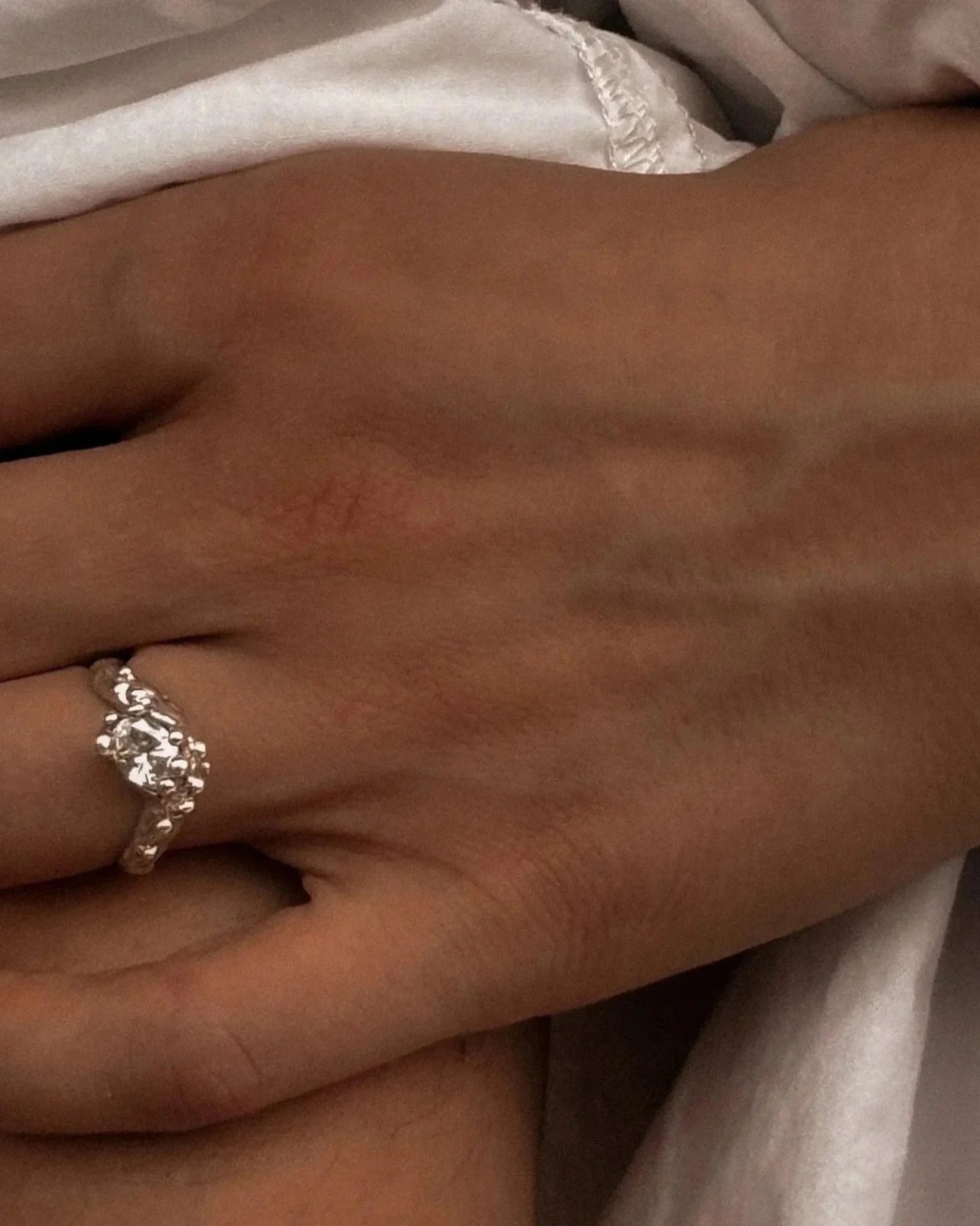 Une main portant une bague en anneau et une chemise blanche. Chic et intemporelle.