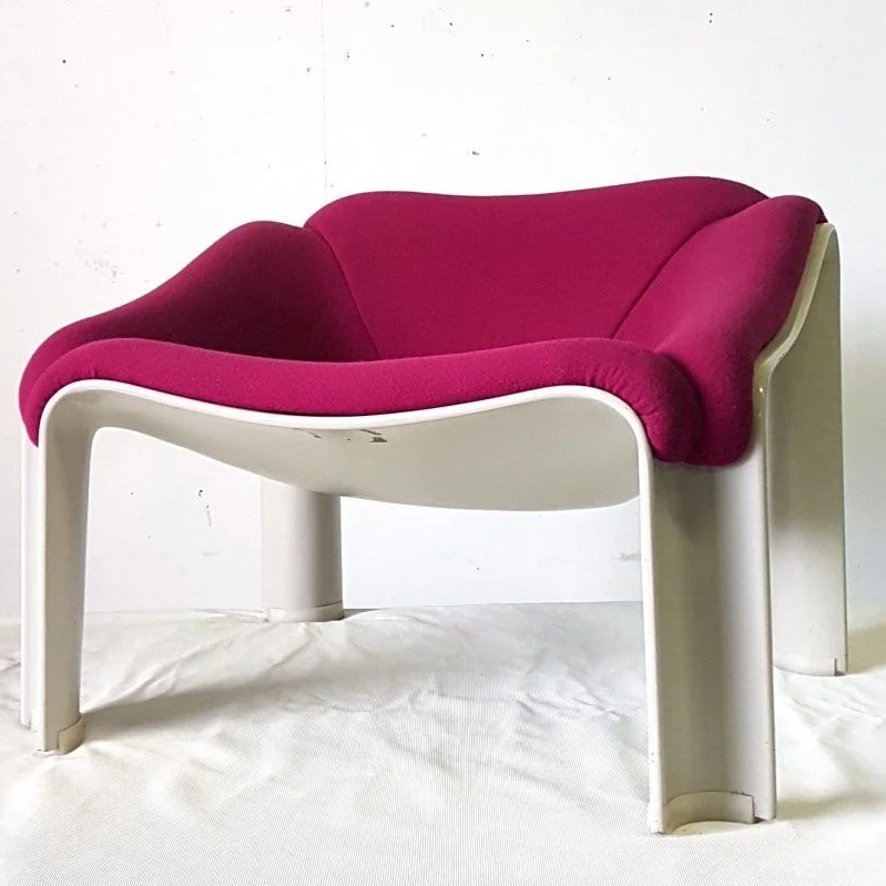 Fauteuil moderniste avec structure blanche organique et confortable et coussins en tissu rose foncé. fait pour épouser la forme du corps.
