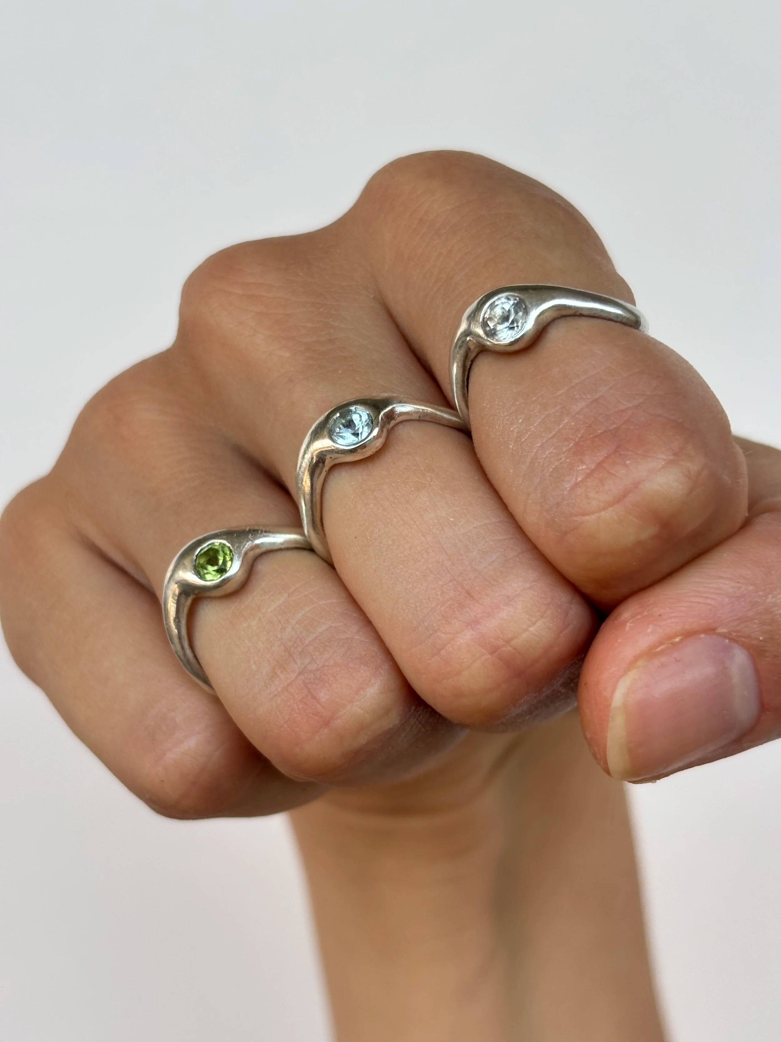 La Bague Elle ose en argent 925 est montrée en trio avec une déclinaison de pierres. Une topaze bleue, une tropaze blanche et un péridot.
