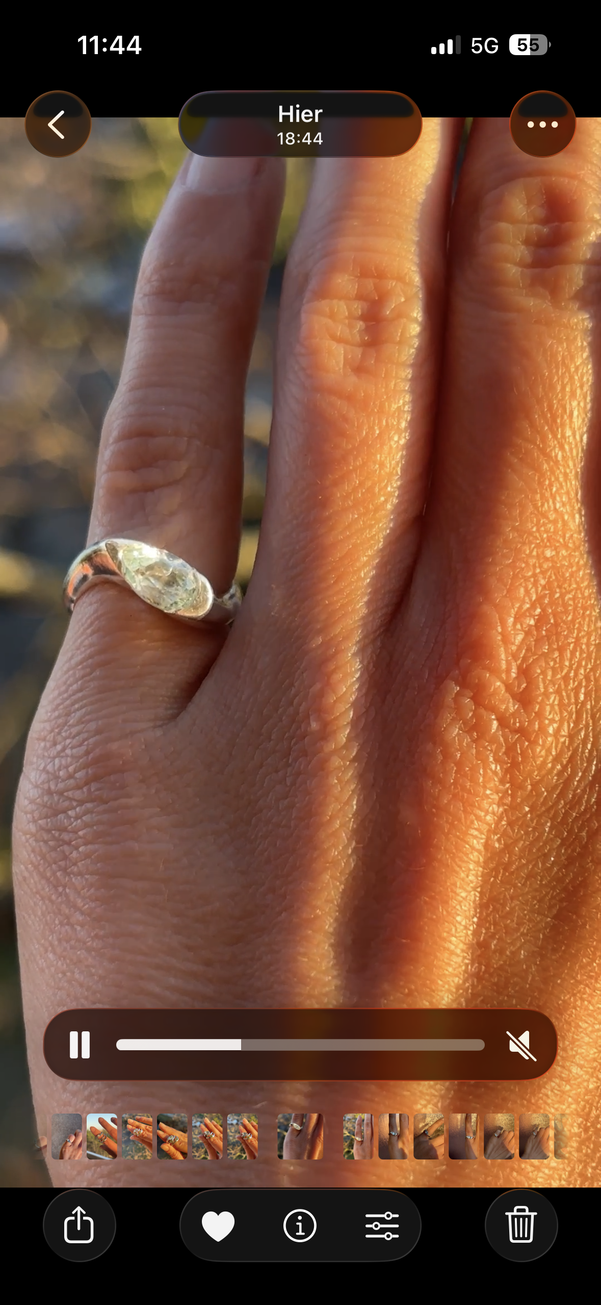 Une main portant une bague en argent avec une pierre transparente, prise en gros plan avec un fond flou.