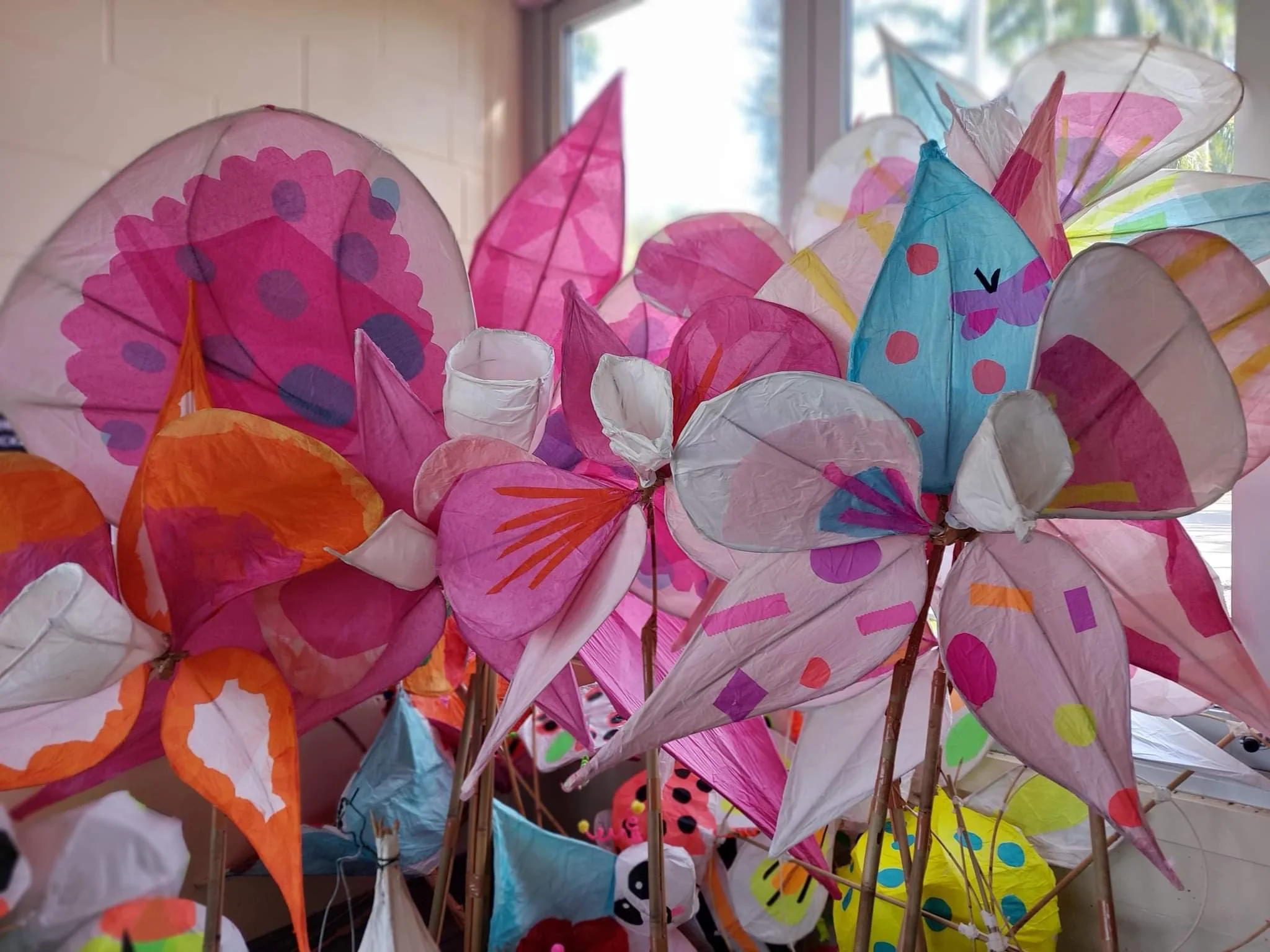 Colorful paper lanterns with polka dot patterns and decorative designs, displayed indoors near a window.