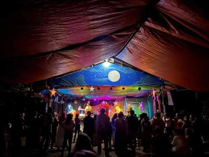 People dancing at a colorful outdoor stage under a tent decorated with stars and a full moon by Lalune Croker Art.