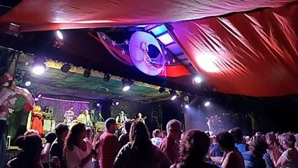 People watching a stage performance with stage decorations by Lalune Croker Art.