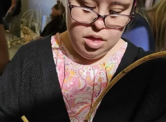 A woman with glasses looking down at something she is holding.