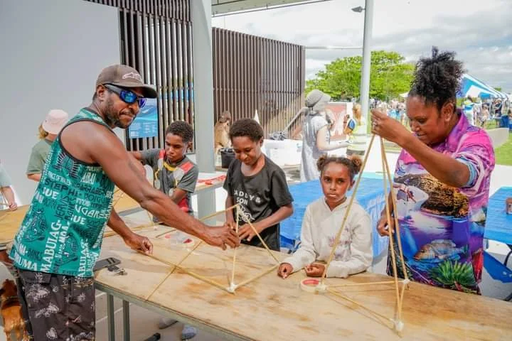 Adults and children participating in a lantern workshop an outdoor event.