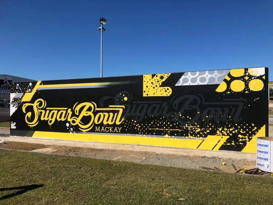 Large sign for Sugar Bowl, a sports or entertainment venue in Mackay, with black and yellow colors, graphic patterns, and bold lettering.