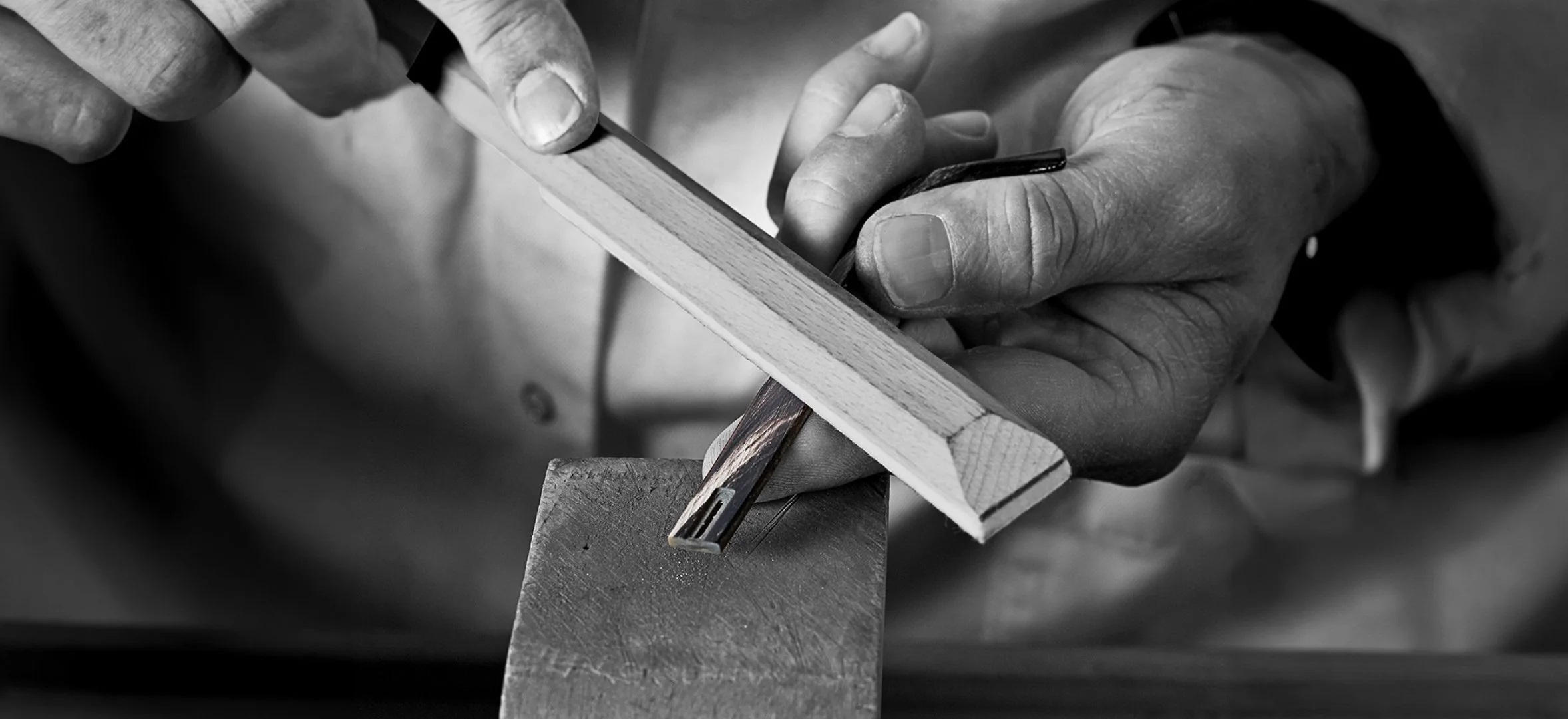Hands working with a saw and wood in black and white