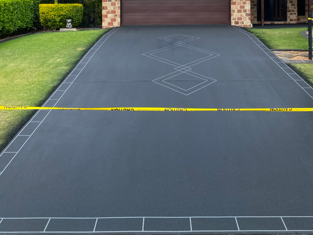 A driveway with a tennis court layout drawn on it, surrounded by a lawn, with a police caution tape across it.