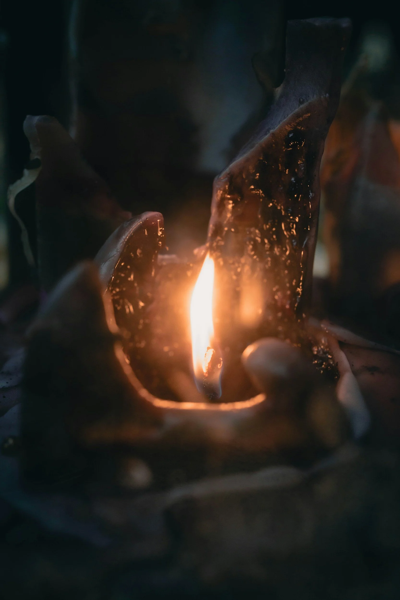 Close-up of a candle flame between metal fire bars, casting a warm glow in the dark.