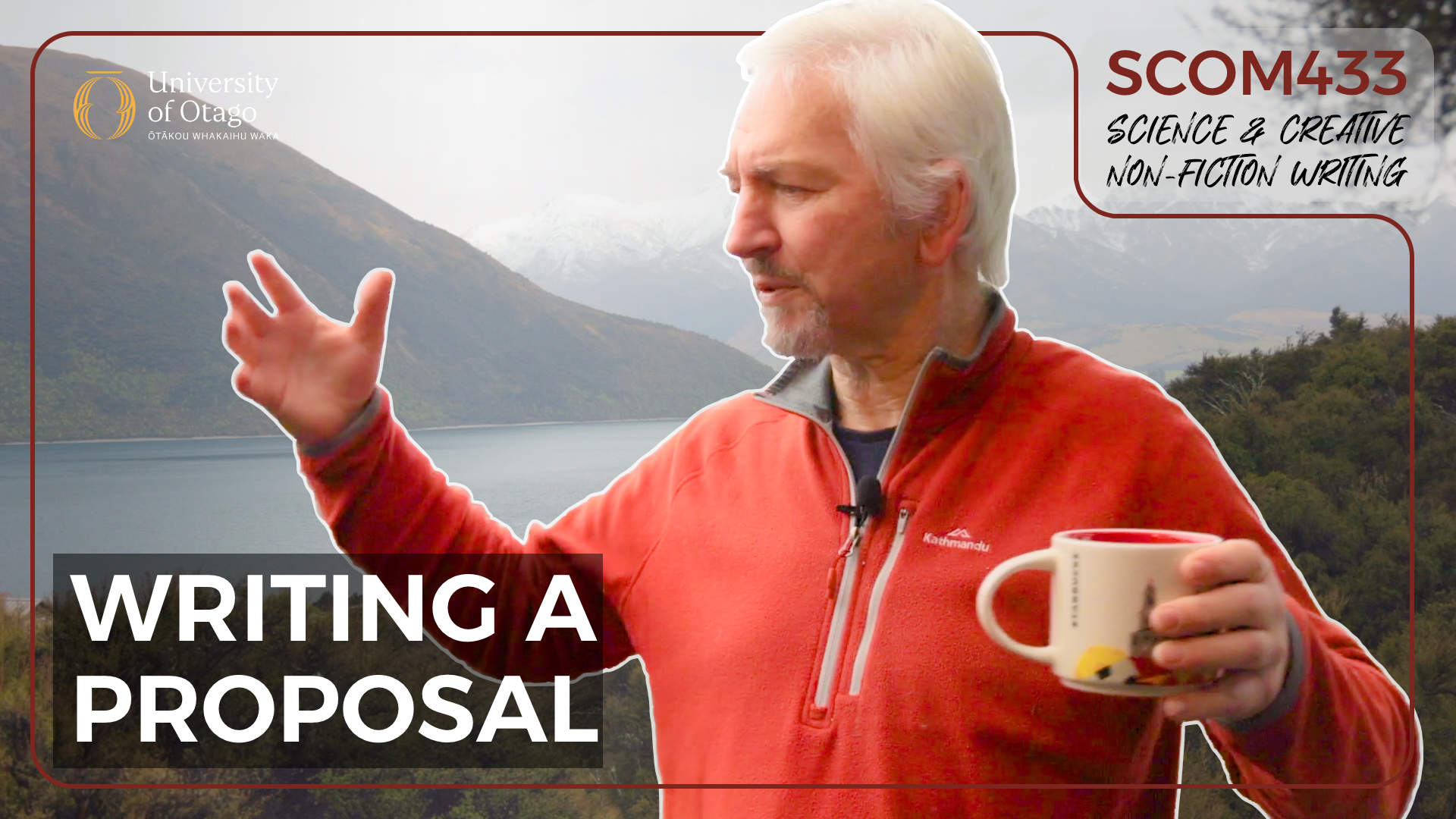 A man with white hair and a beard wearing a red jacket holding a mug in one hand and gesturing with his other hand in front of a mountain landscape with a lake.