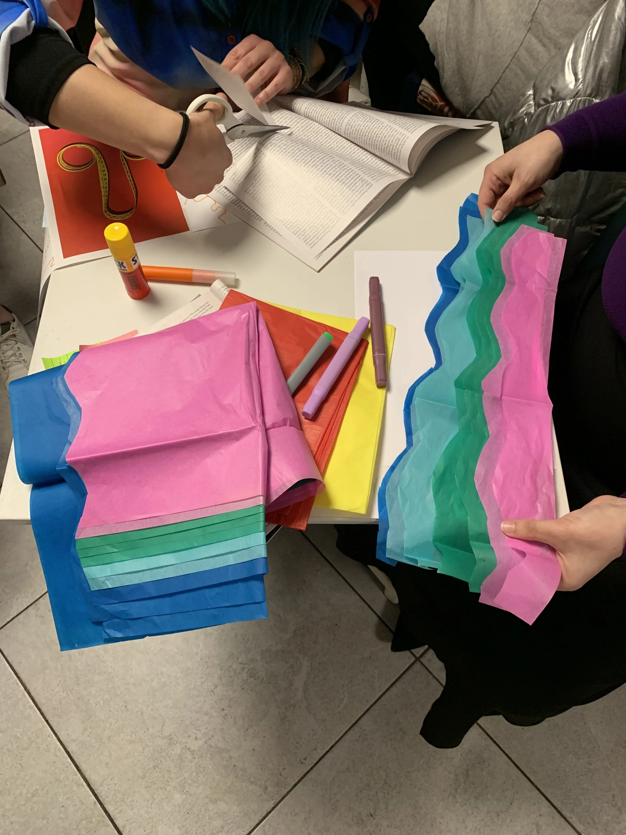 Arte e artigianato con materiali colorati, forbici e colla su un tavolo.