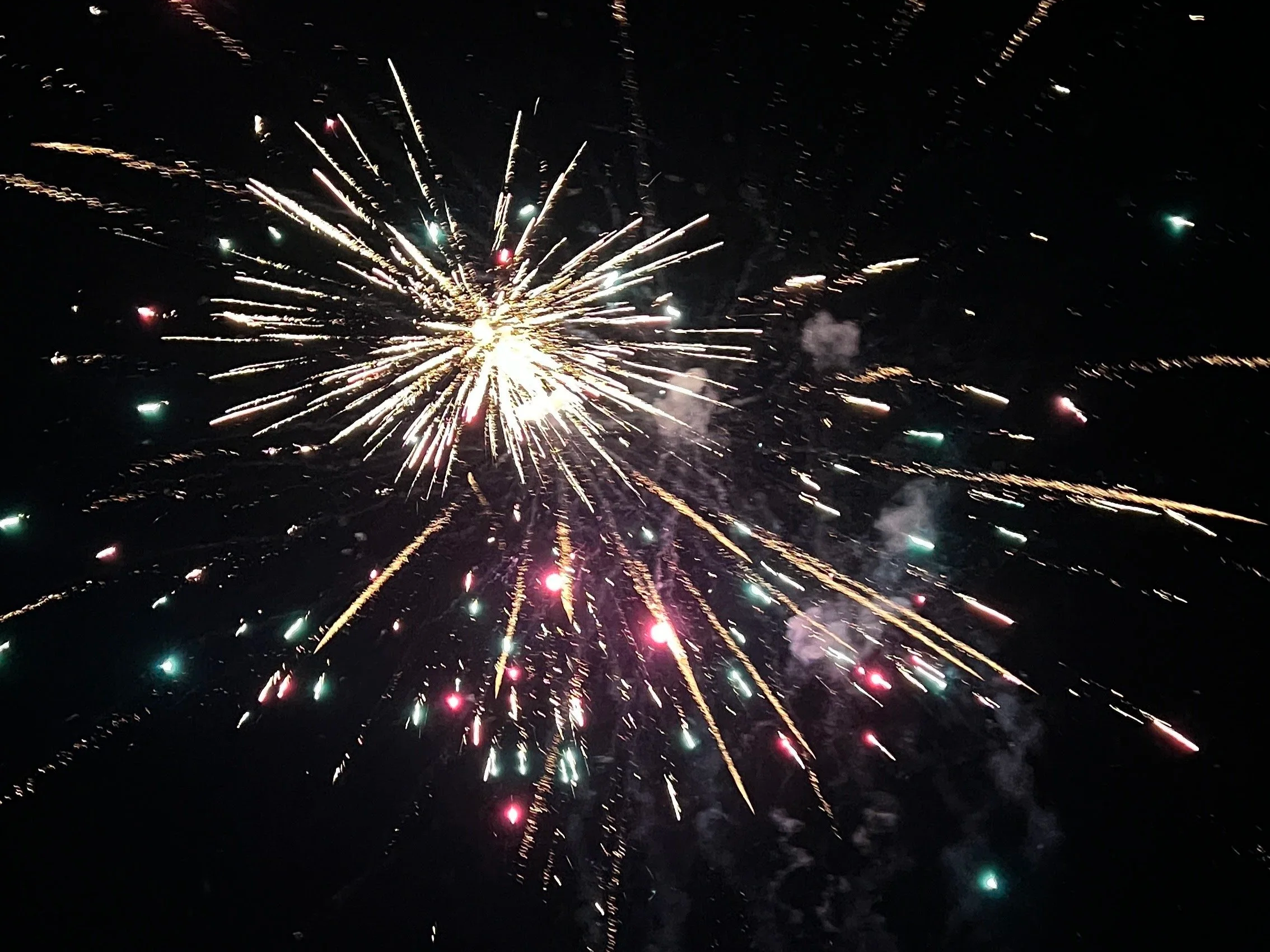 Colorful fireworks exploding in the night sky with streaks of light radiating outward.