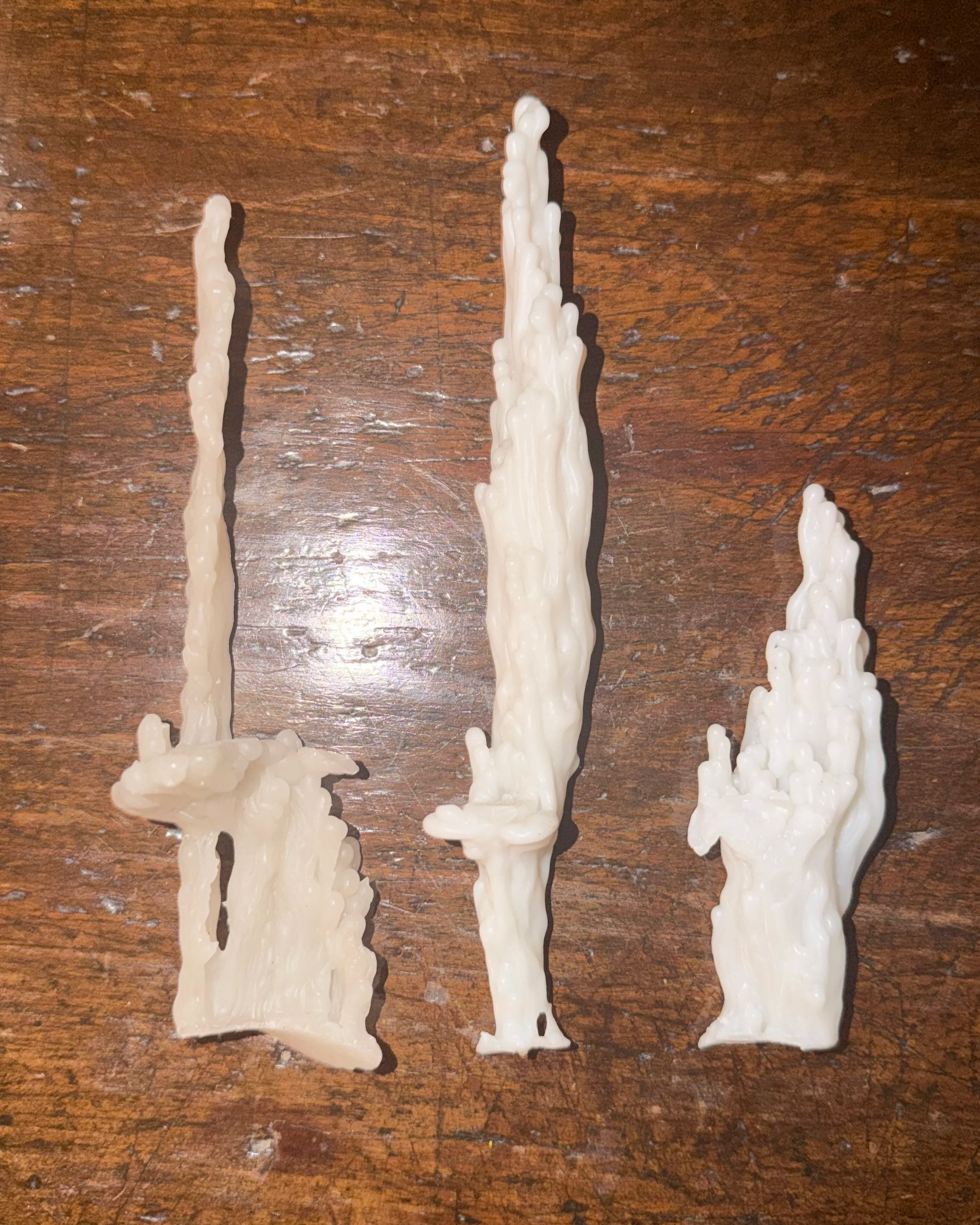 Three white candle drippings on a wooden surface.
