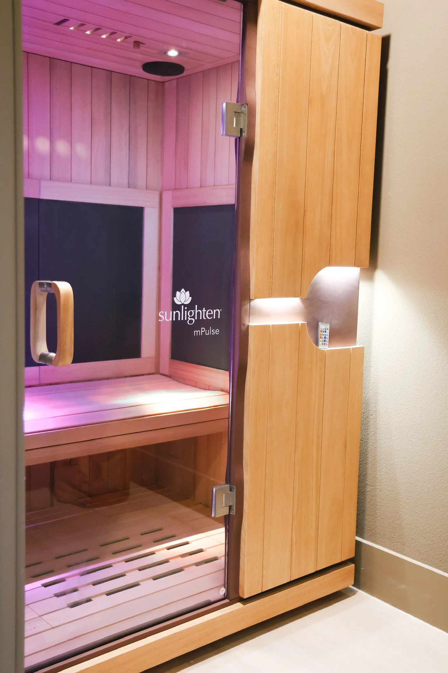 Open wood-paneled Sunlighten infrared sauna with illuminated interior and built-in control panel.