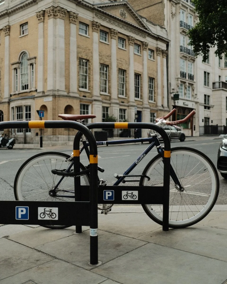 Bicycle locked to a bike rack on a city sidewalk in front of a historic building.