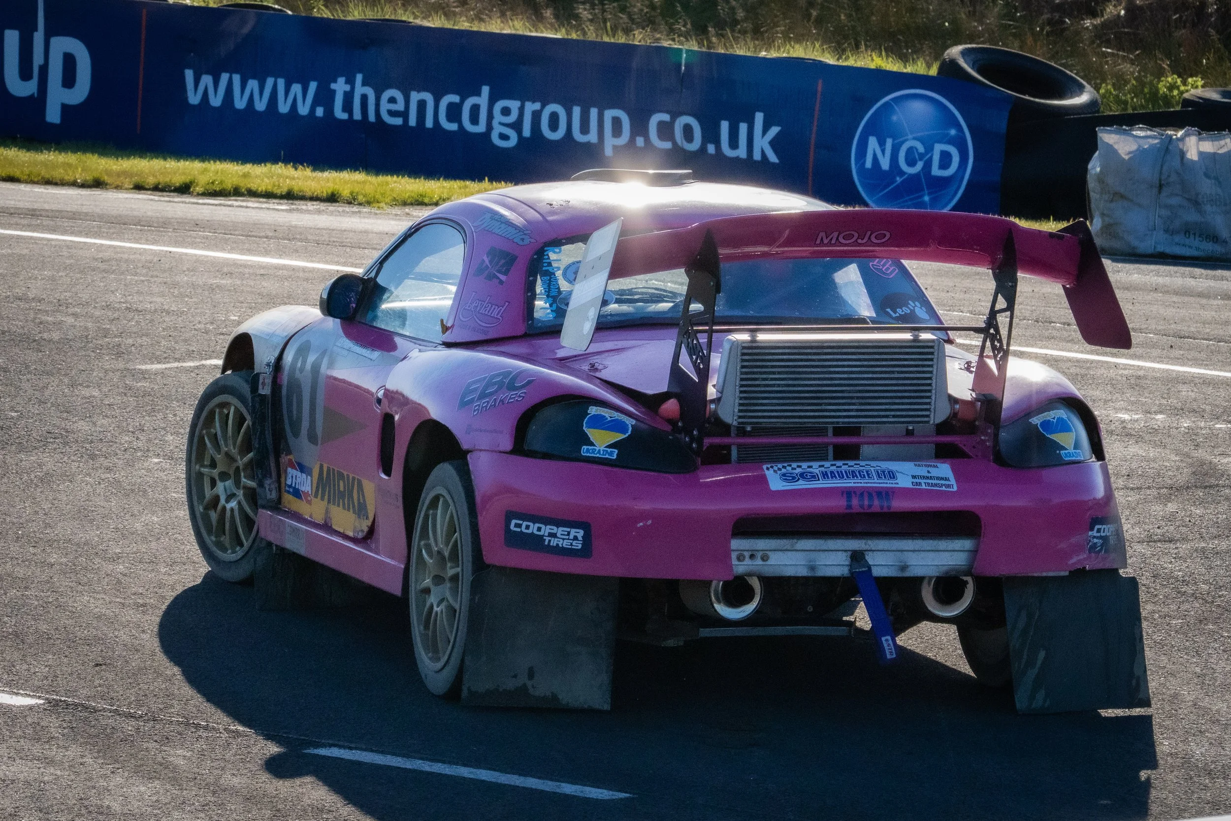 Pink race car at a rallycross event at Knockhill in Scotland, with a large rear wing.