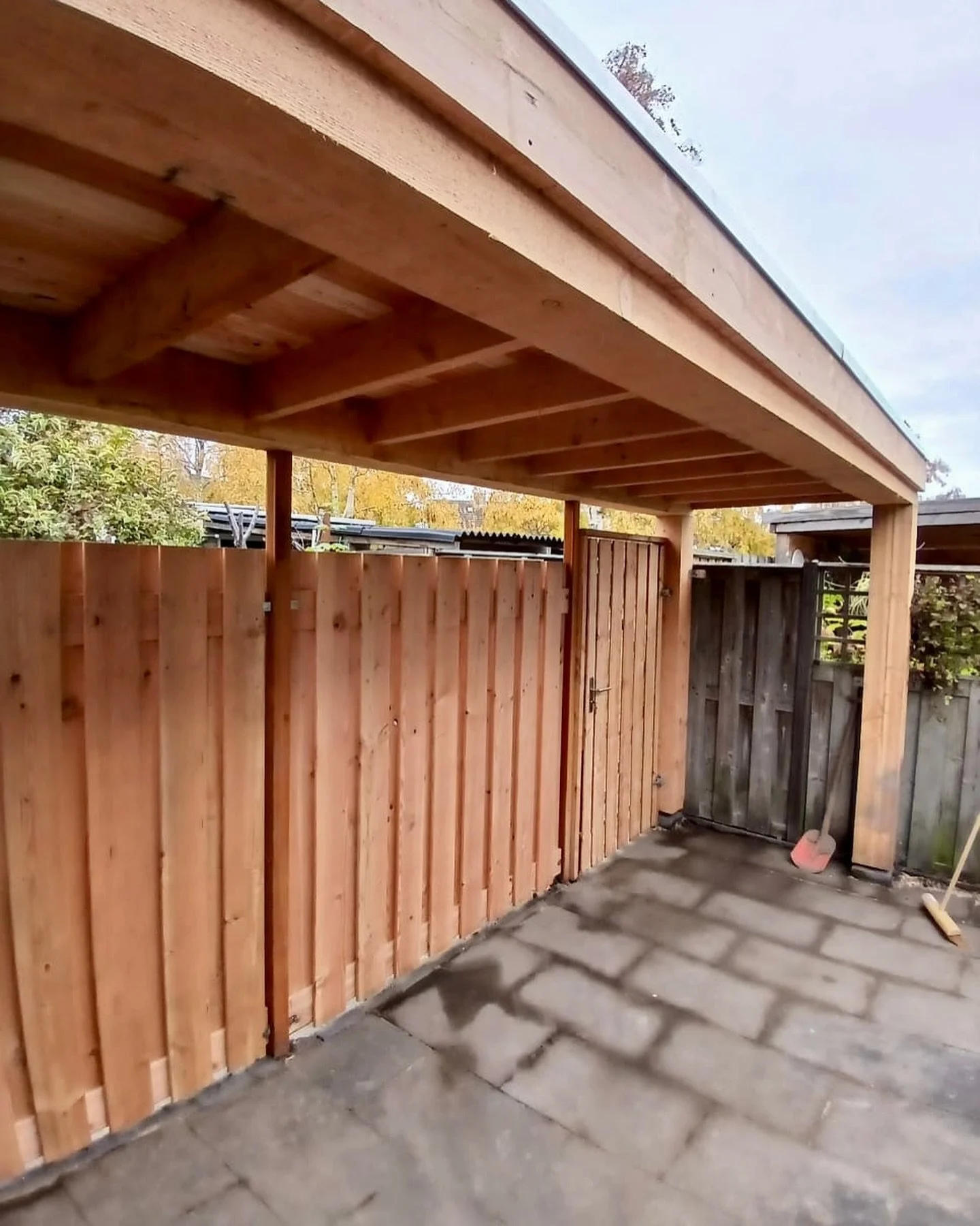 Buitenkant van een houten tuinpoort met een douglas houten overkapping.