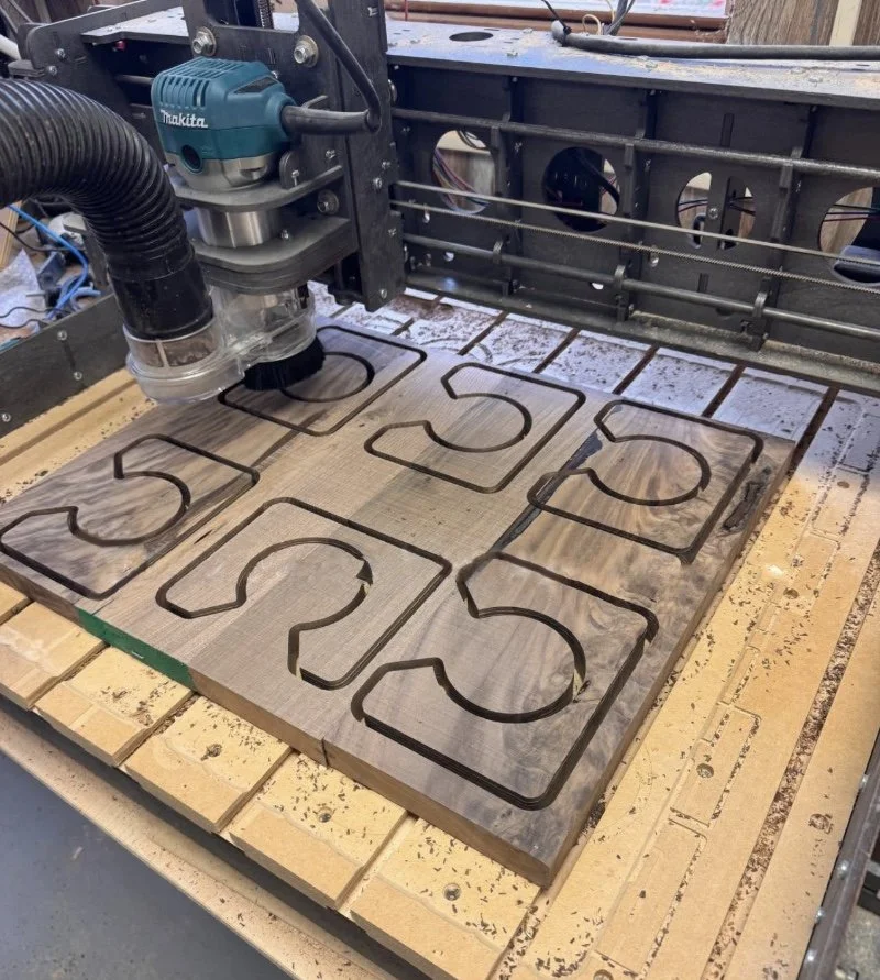 A CNC machine is carving numbers '5', '6', '7', and '8' with a router bit into a wooden board.