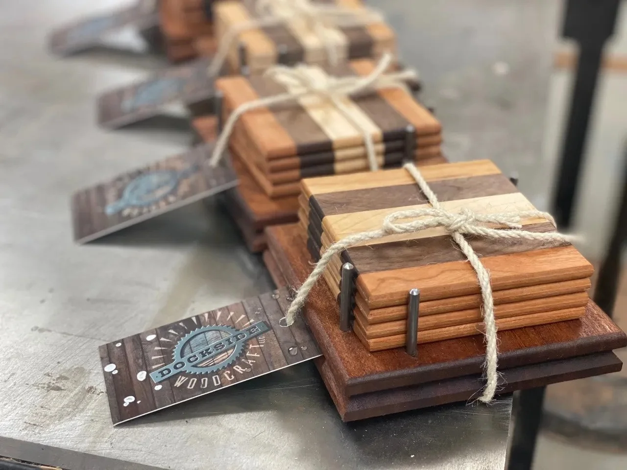 Stacks of small wooden cutting boards tied with string, with a business card that reads 'Dockside Woodcraft' placed nearby.