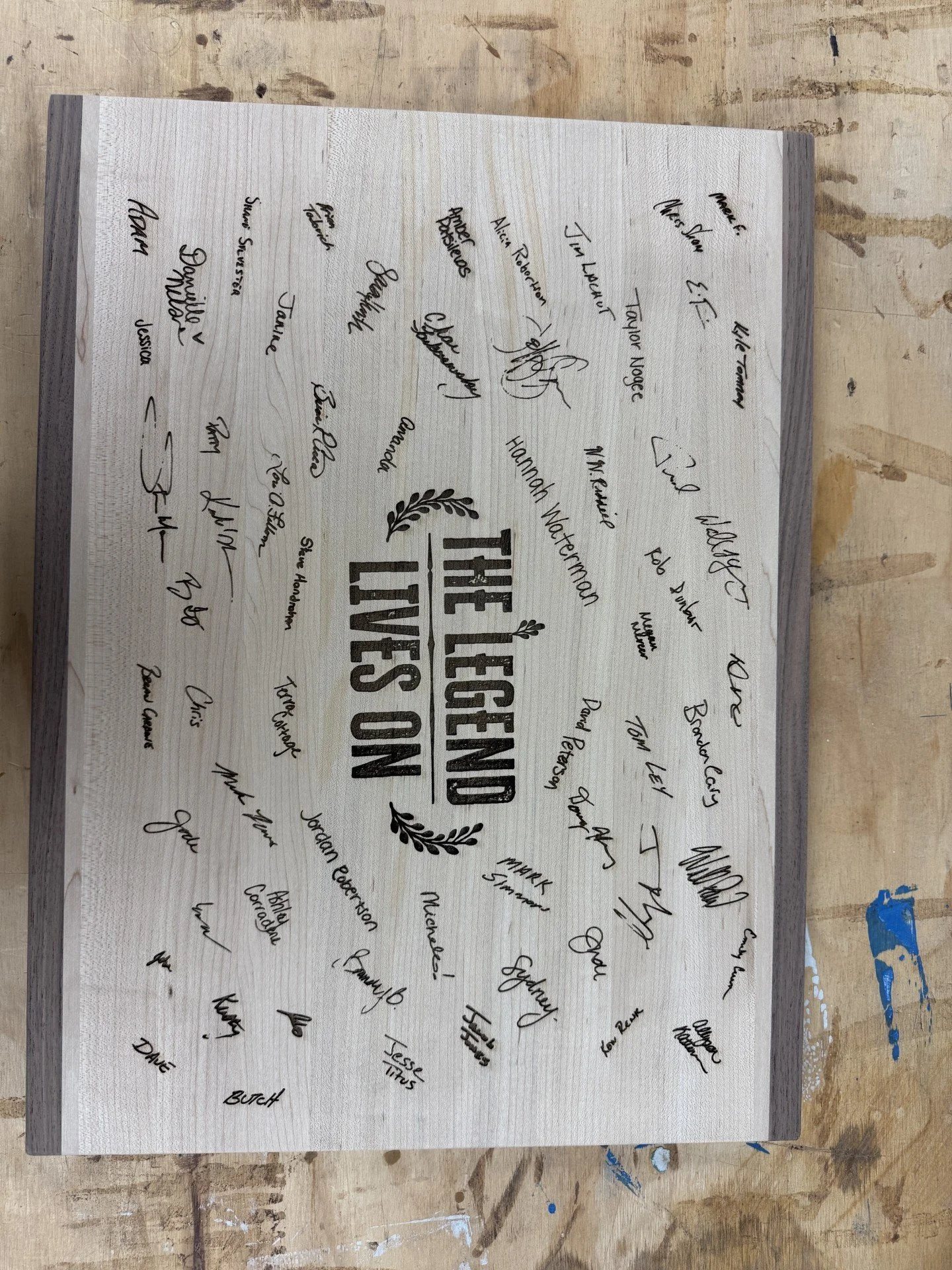 A wooden sign with the text "The Legend Lives On" surrounded by signatures from various individuals.