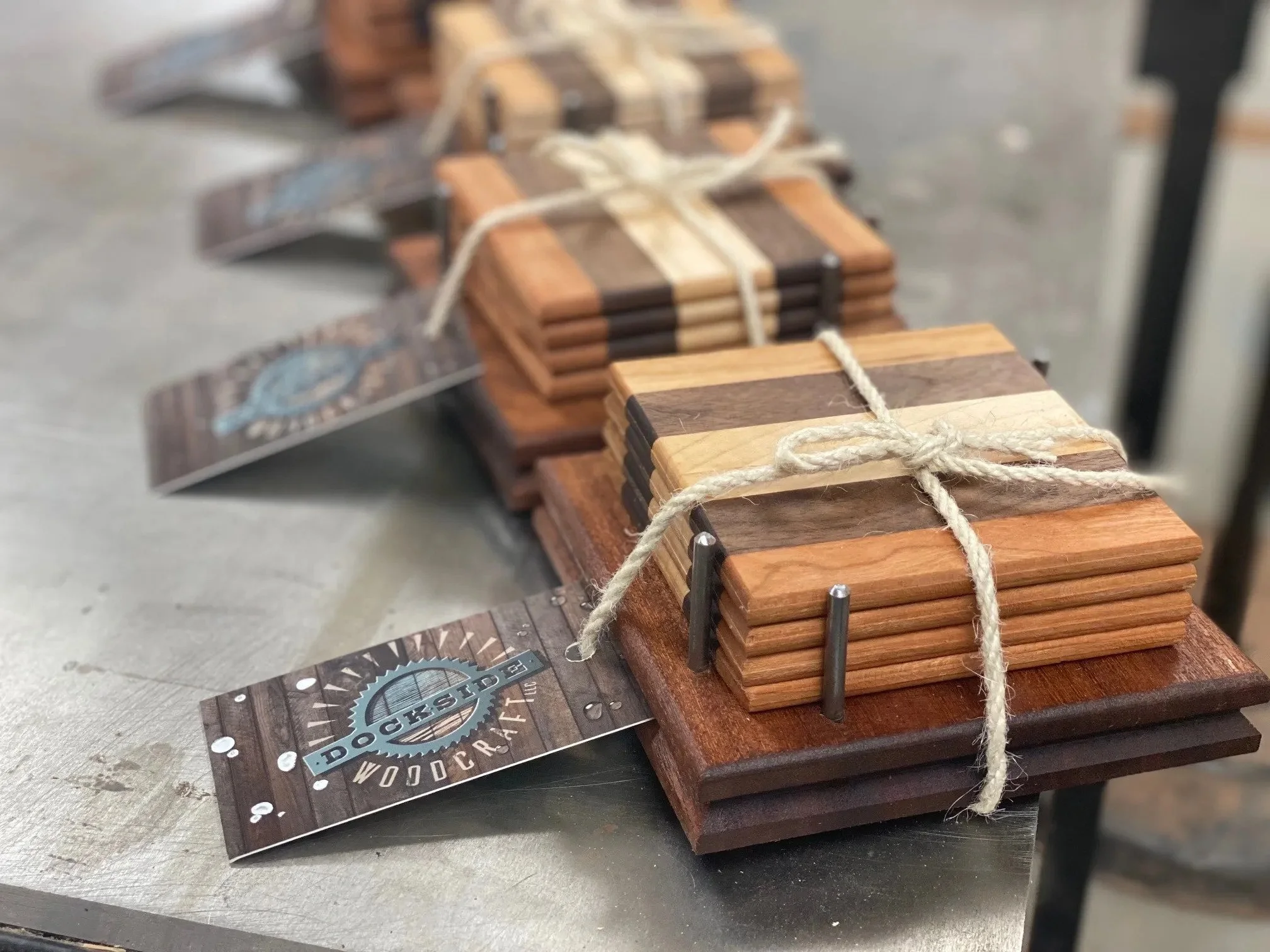 Bundles of small wooden cutting boards tied with string, displayed on a table at a craft fair or market.
