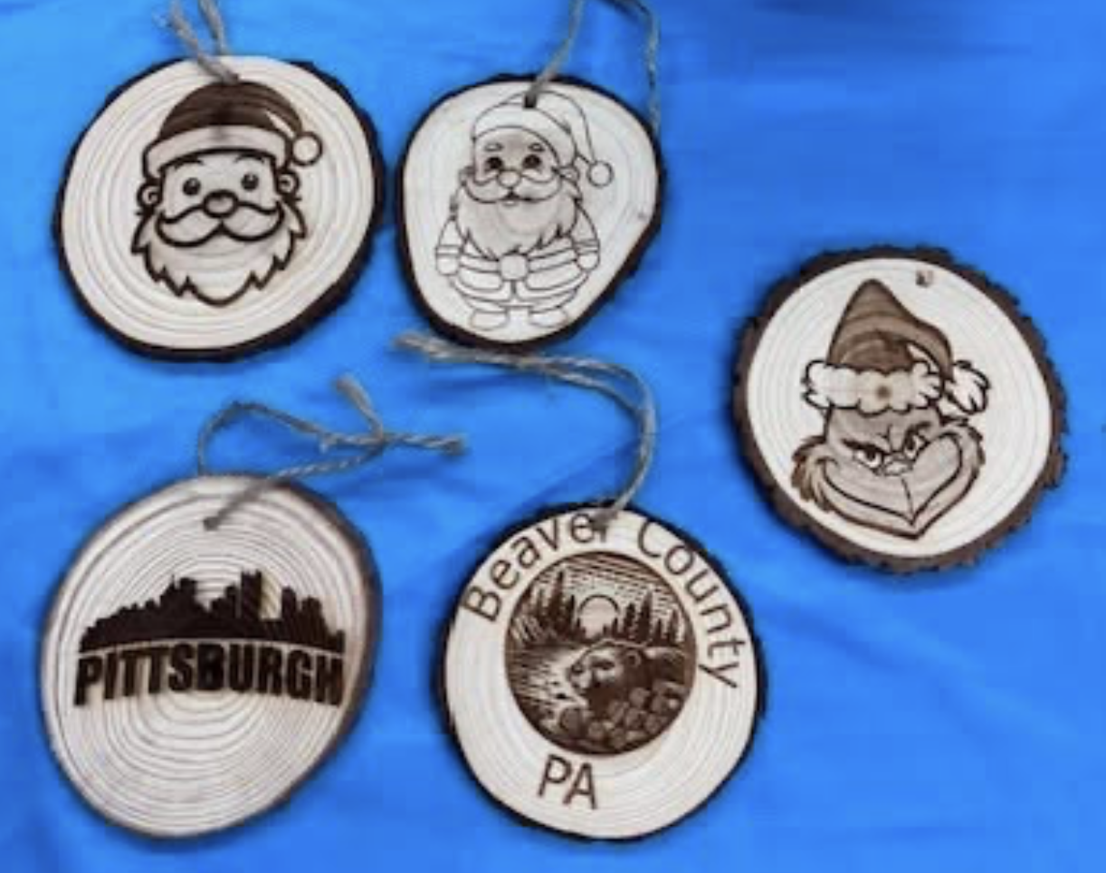Set of five wooden Christmas ornaments with engraved holiday and Pittsburgh-themed designs, hung on blue background.