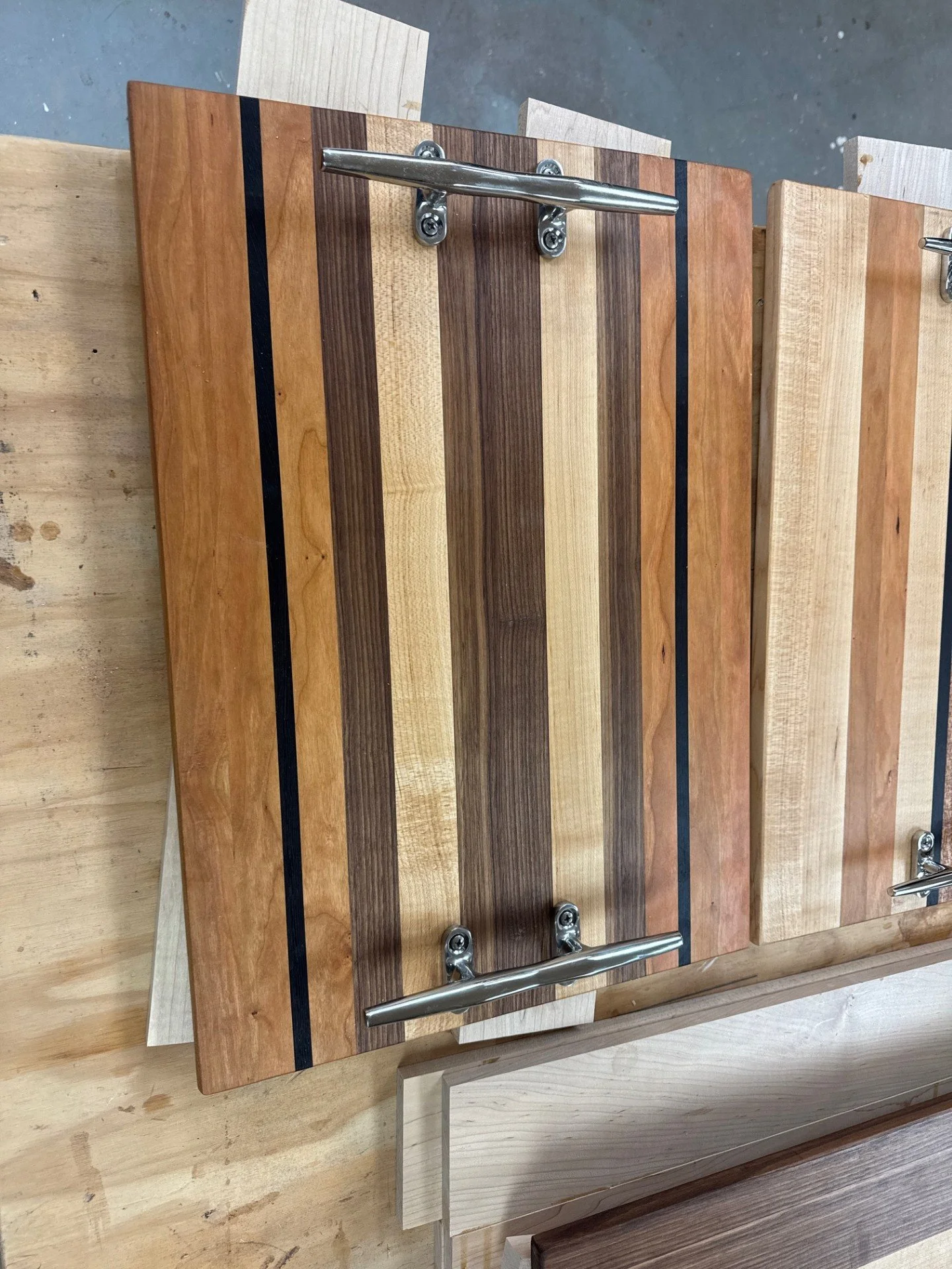 Multiple wooden cutting boards with metal handles, arranged on a work surface.