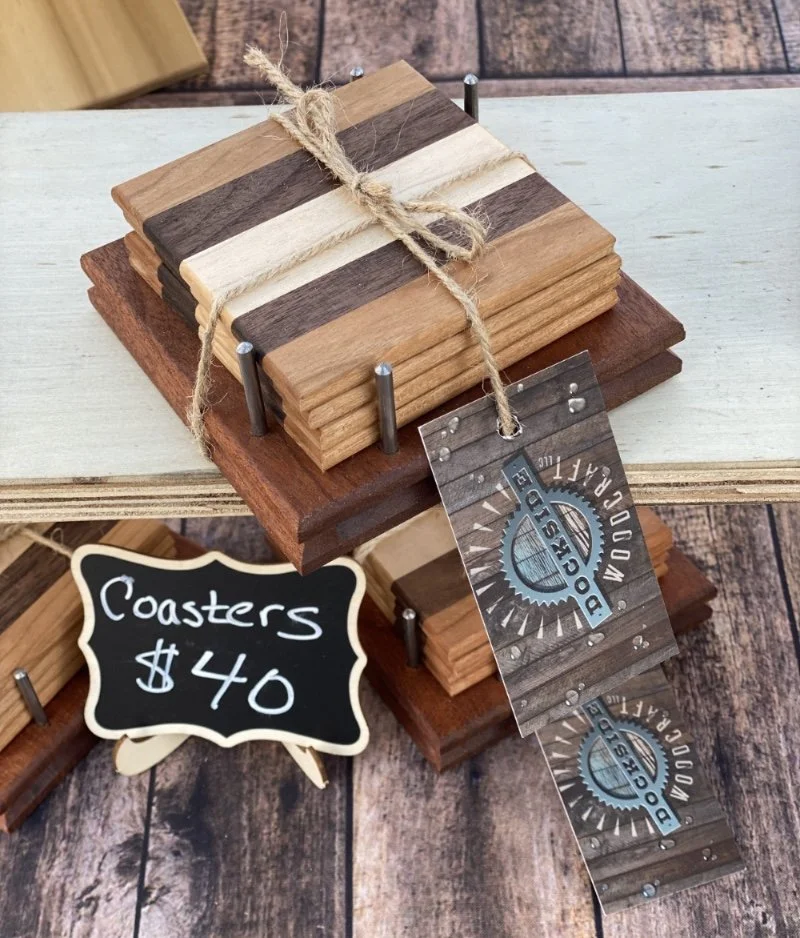 Stack of wooden coasters tied with twine, displayed on a wooden board with a sign indicating they cost $40.