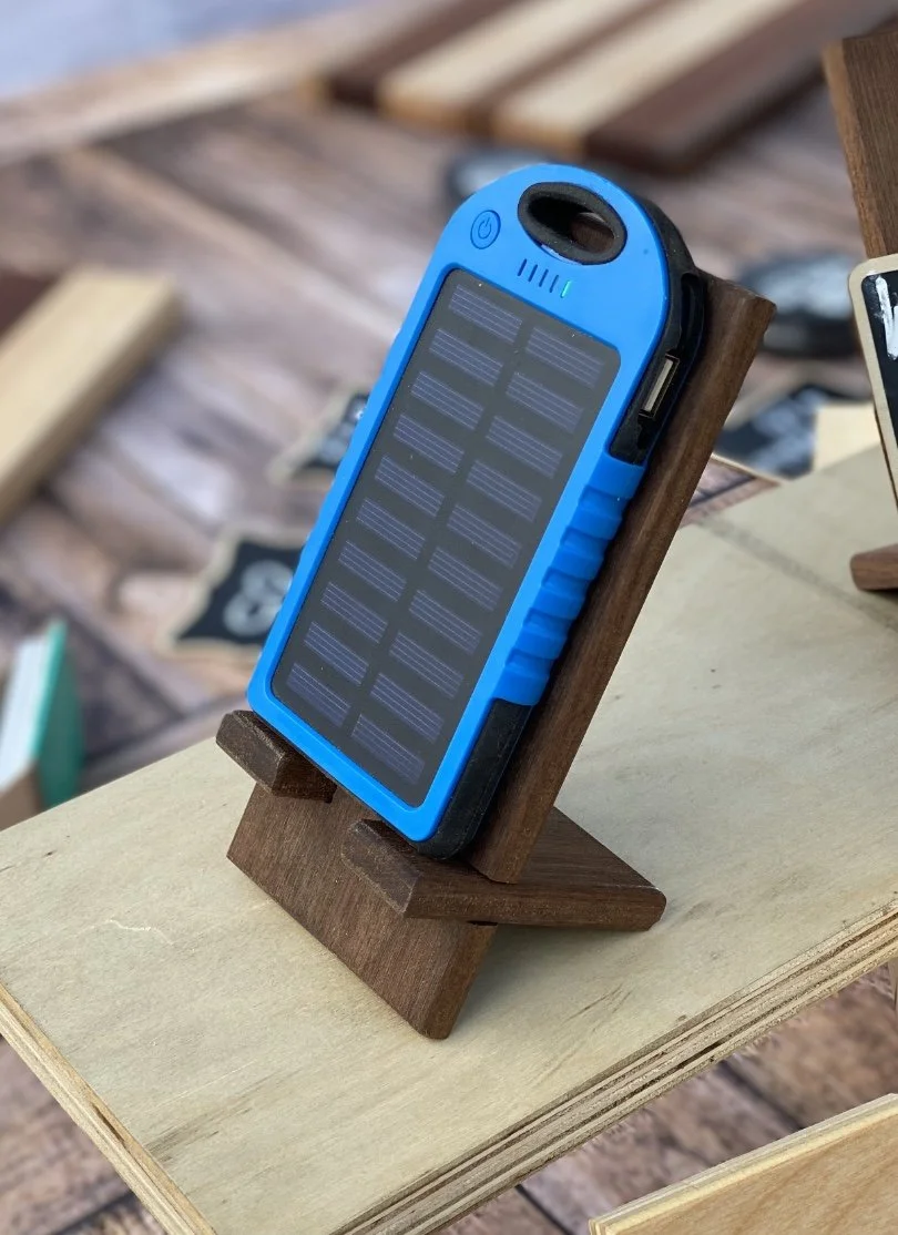 Portable solar charger with a blue casing, displayed on a wooden stand.
