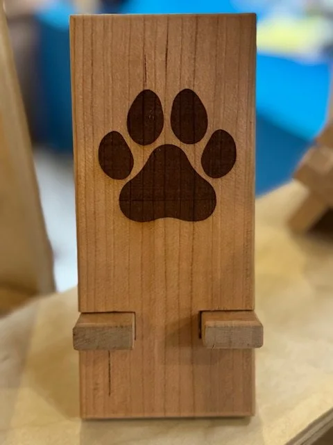 A wooden box with a paw print engraved on it, positioned upright on a flat surface.